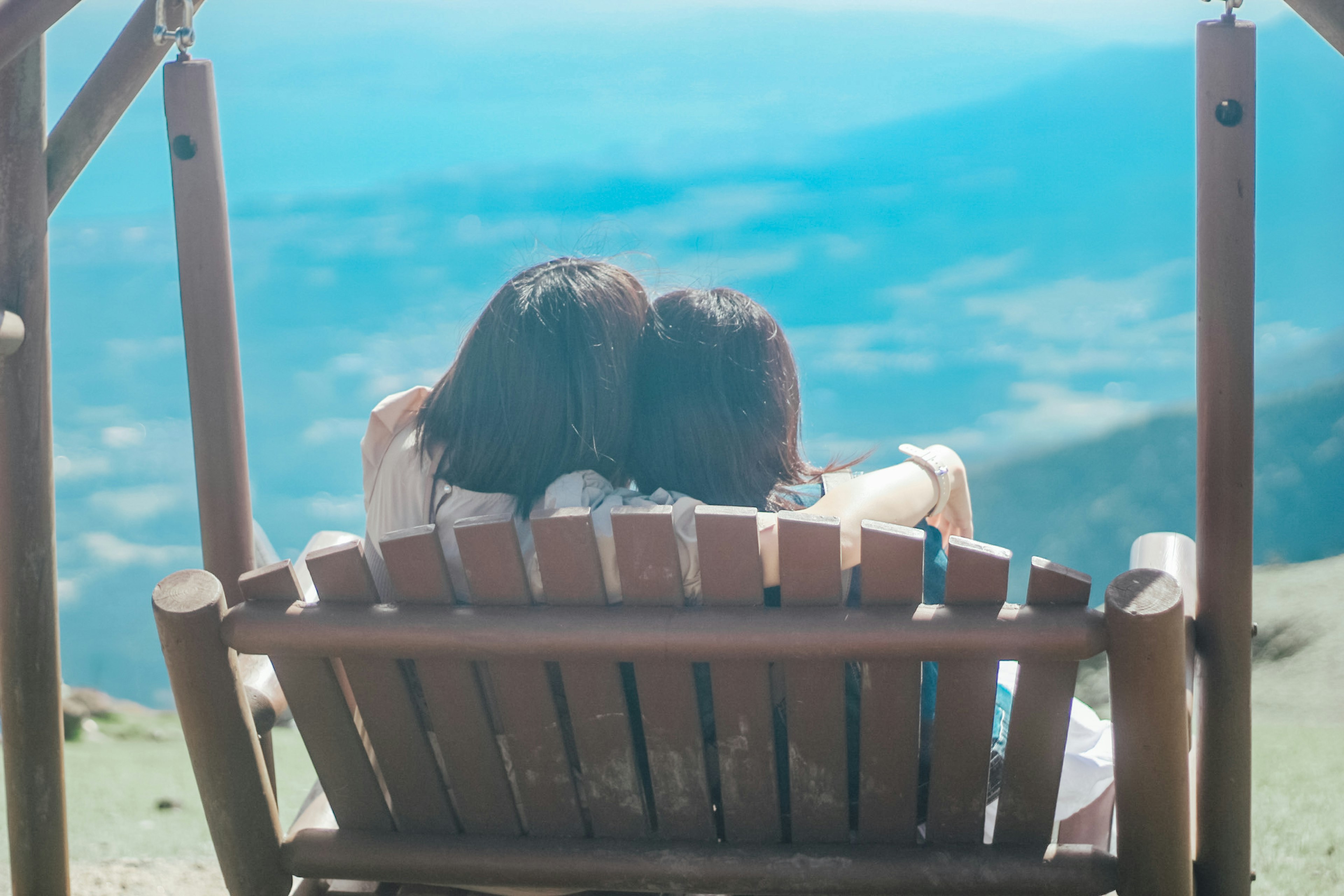 Deux femmes assises sur un banc en bois admirant une vue sur la montagne