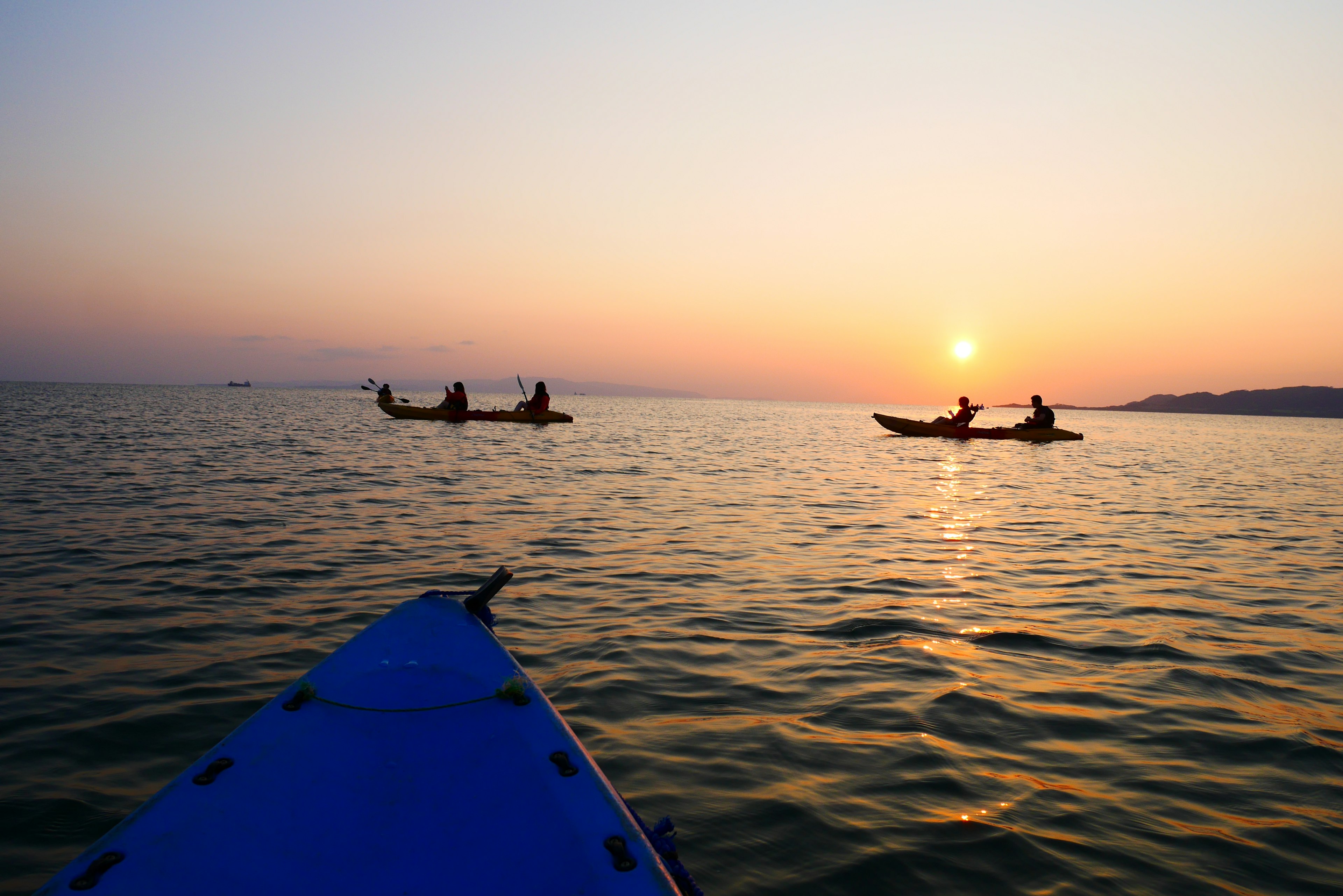 Kayakers paddling on a tranquil sea at sunset