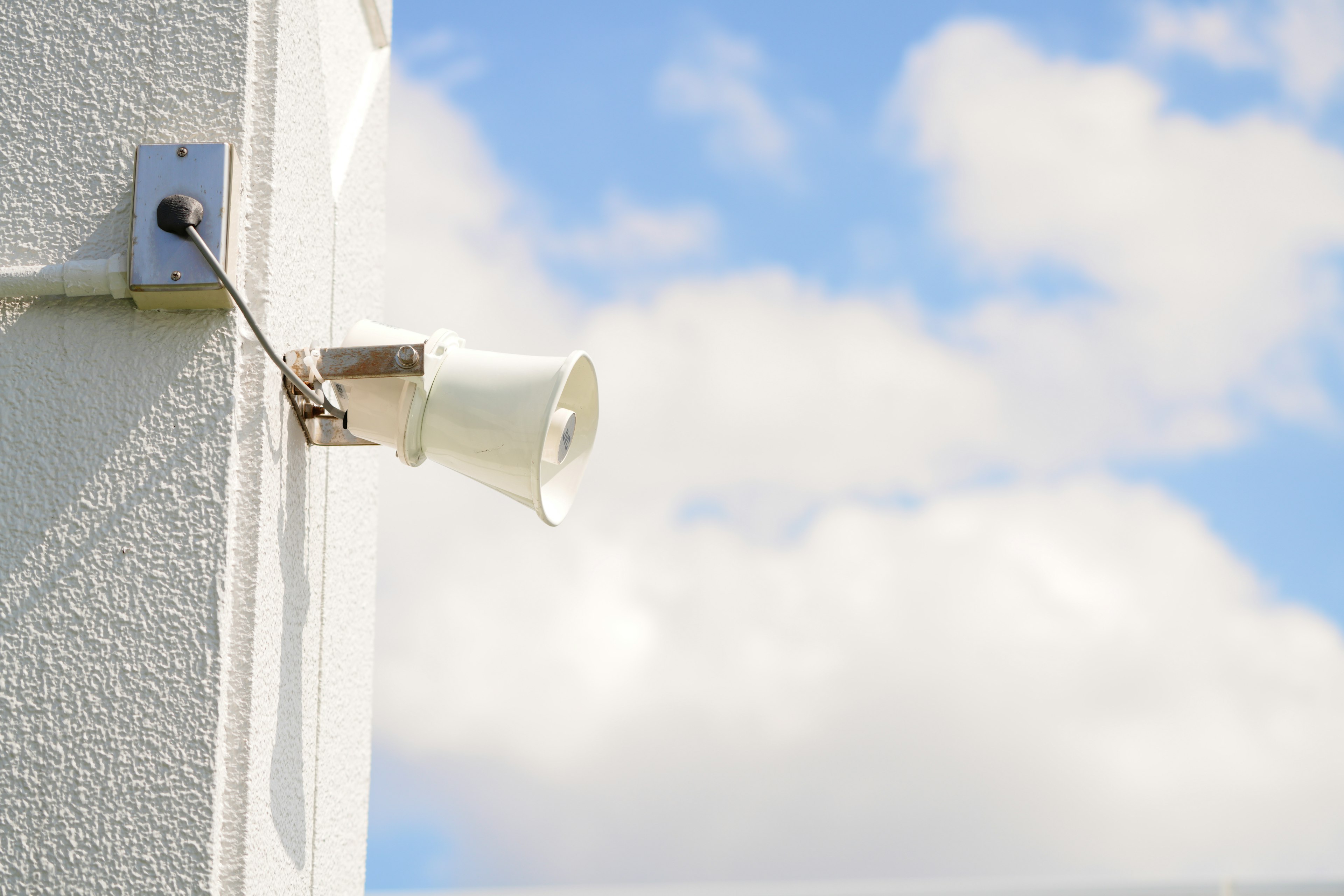 Haut-parleur fixé sur un mur blanc avec un ciel bleu