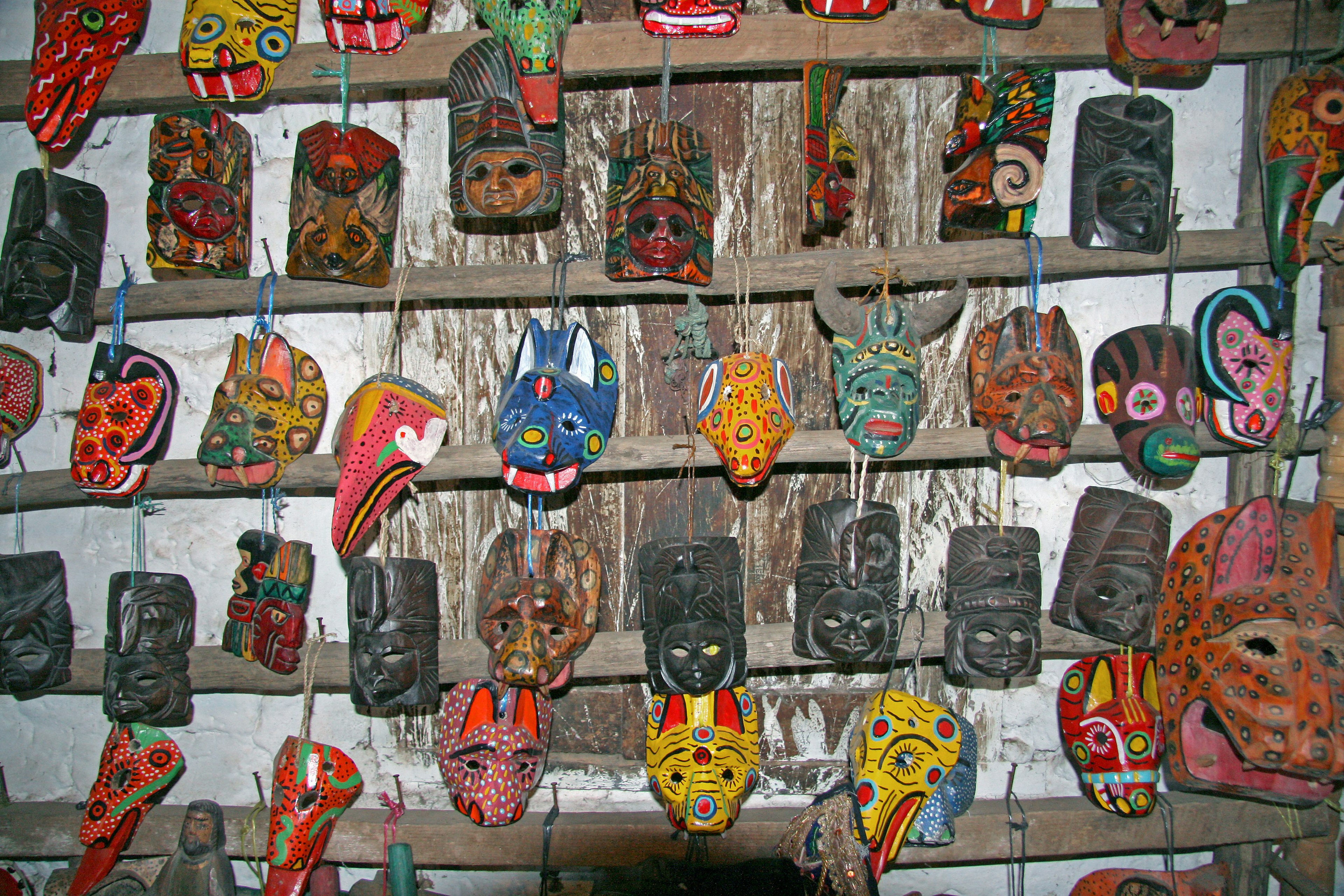 Máscaras coloridas dispuestas en una estantería de madera