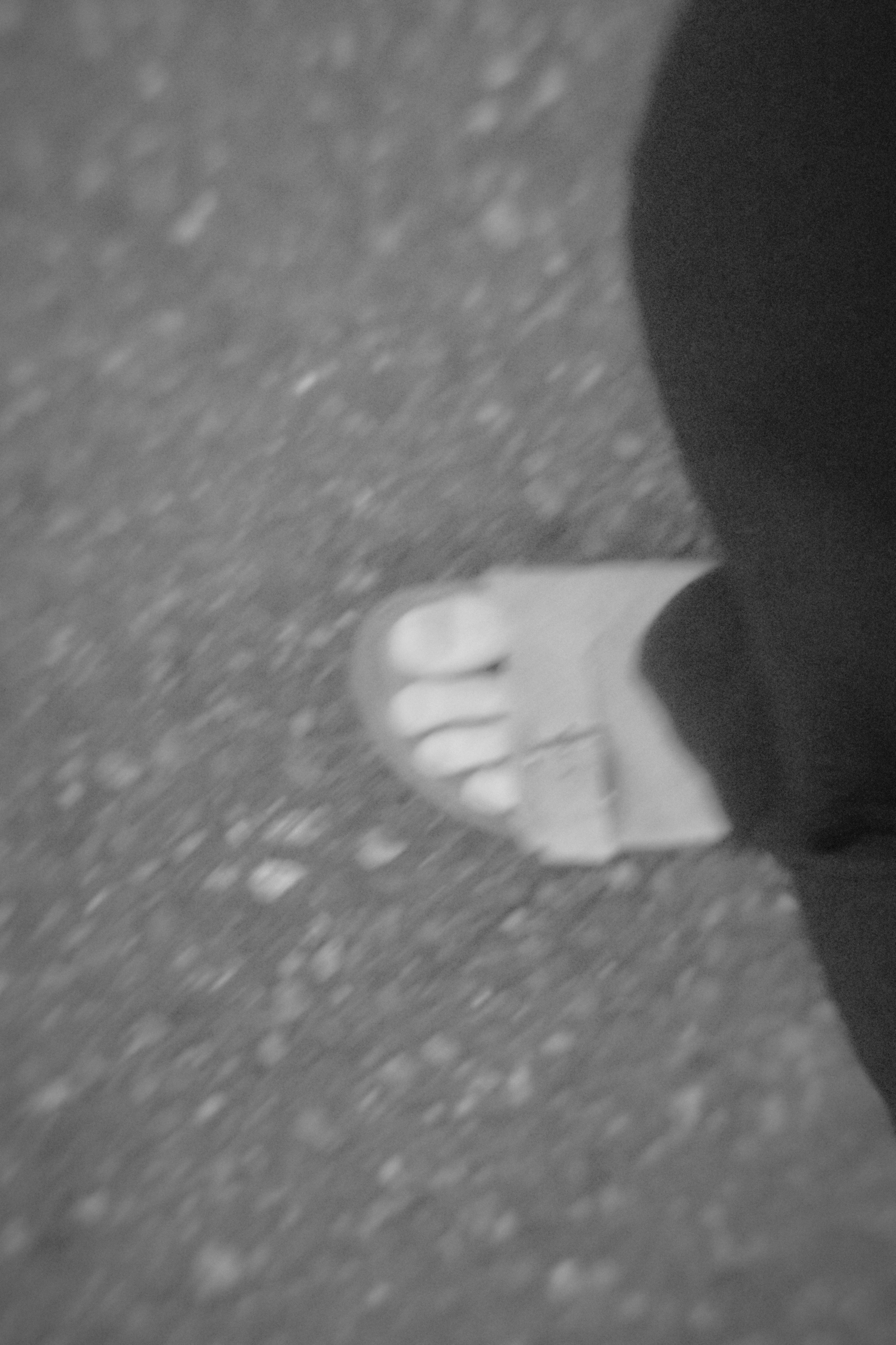 A foot wearing a sandal with visible toes placed on the ground in black and white