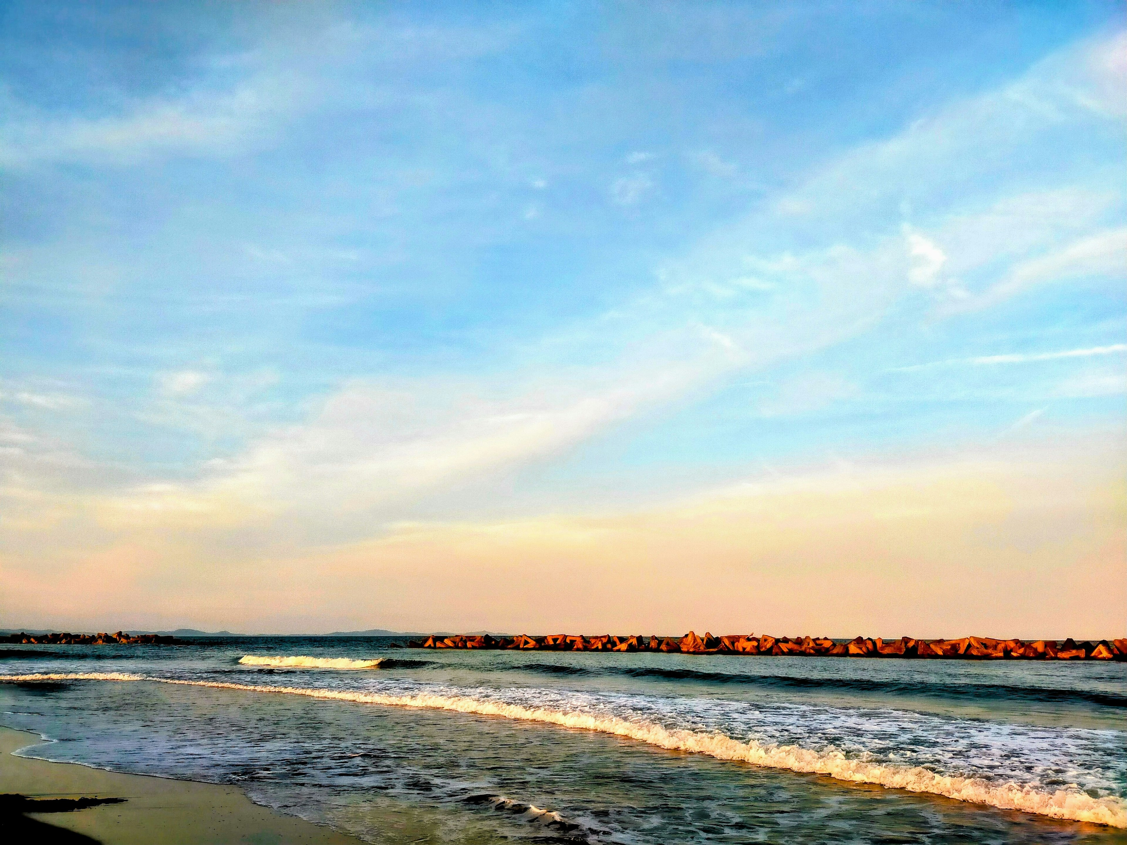 Pemandangan pantai yang tenang dengan langit biru dan ombak lembut