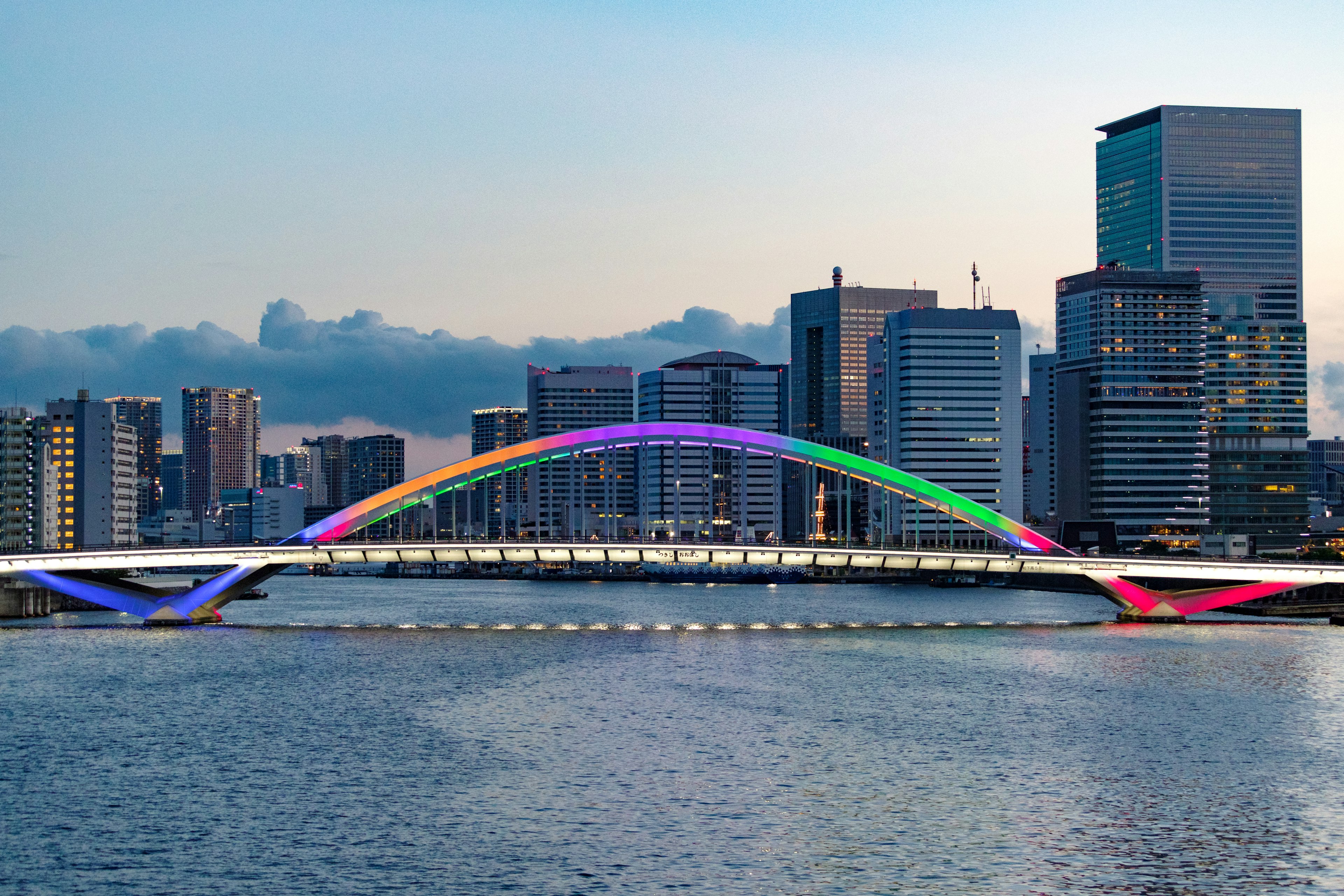 Bellissimo ponte ad arco color arcobaleno con skyline cittadino