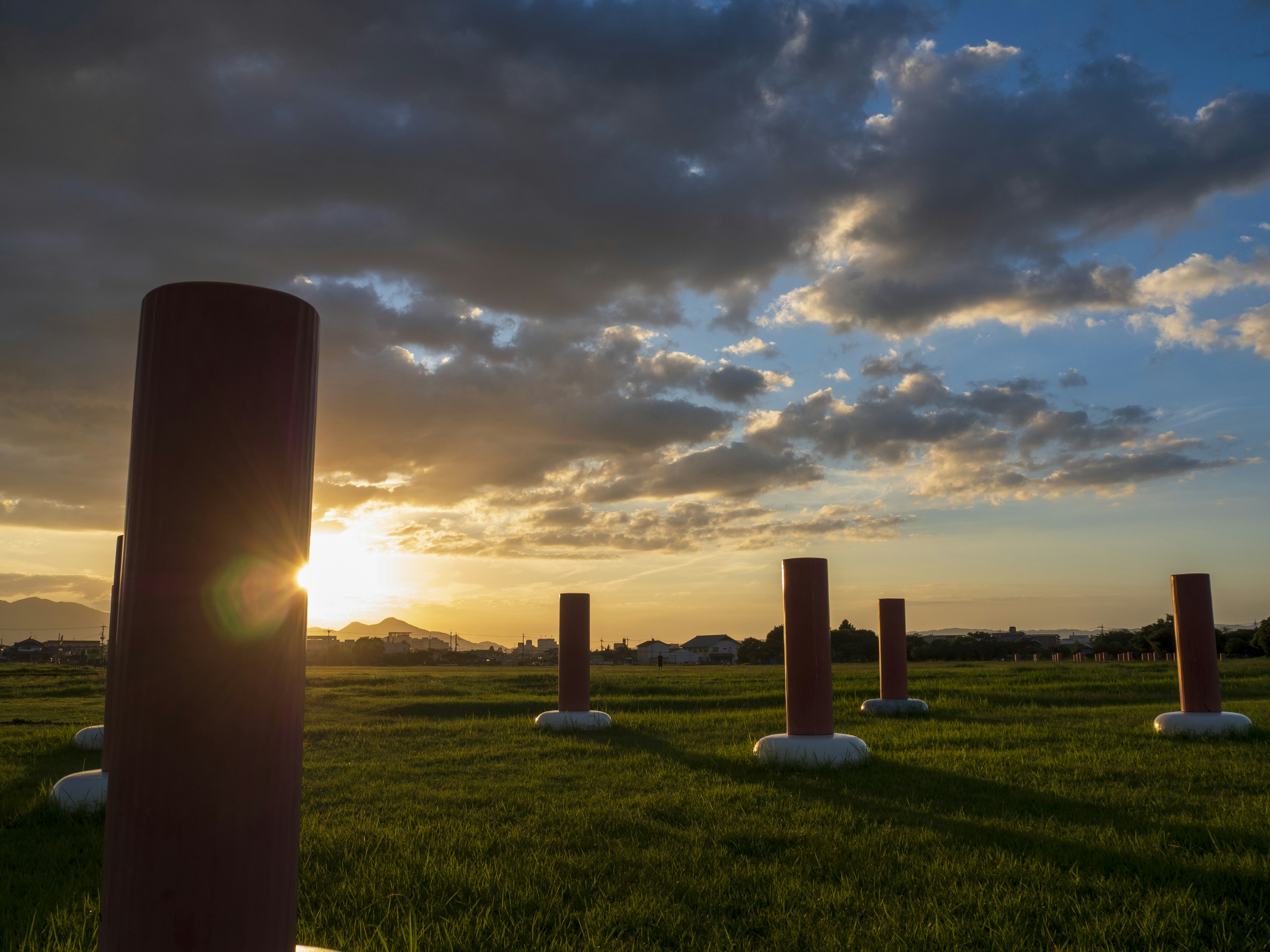 Row of red pillars against a sunset and cloudy sky