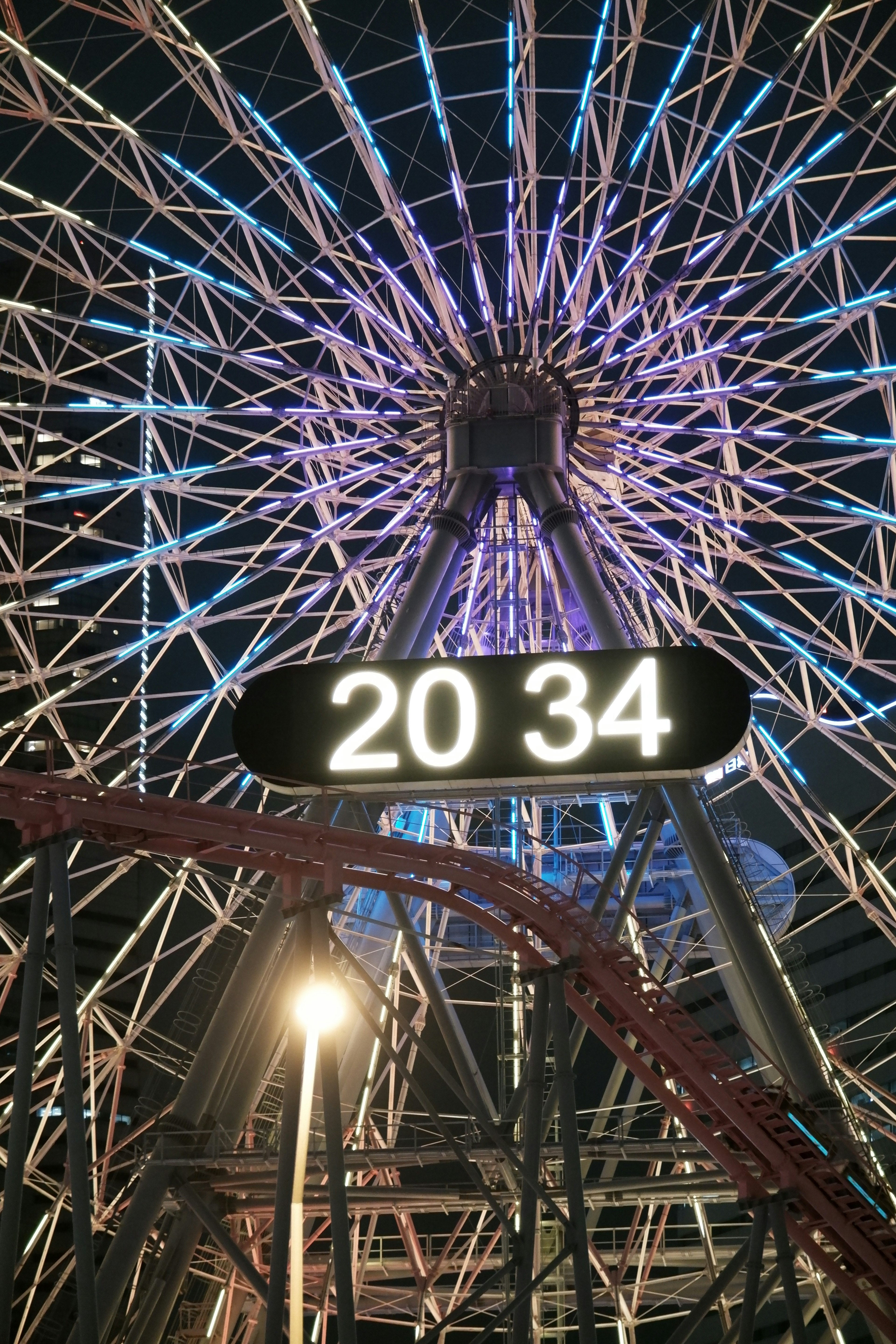 Nachtsicht auf ein Riesenrad mit der Nummer 2034 und bunten Lichtern