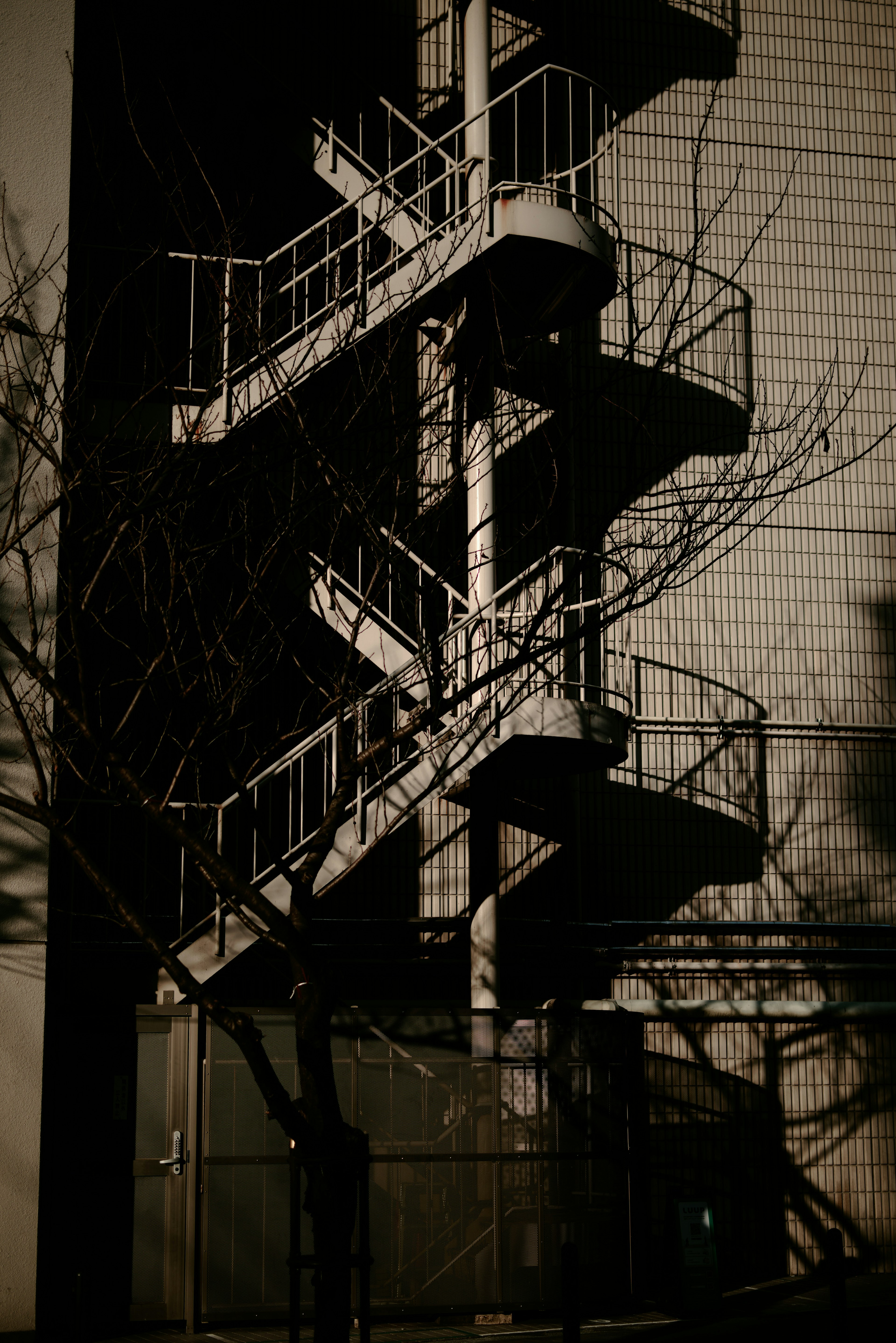 Metal fire escape staircase attached to building side with shadows