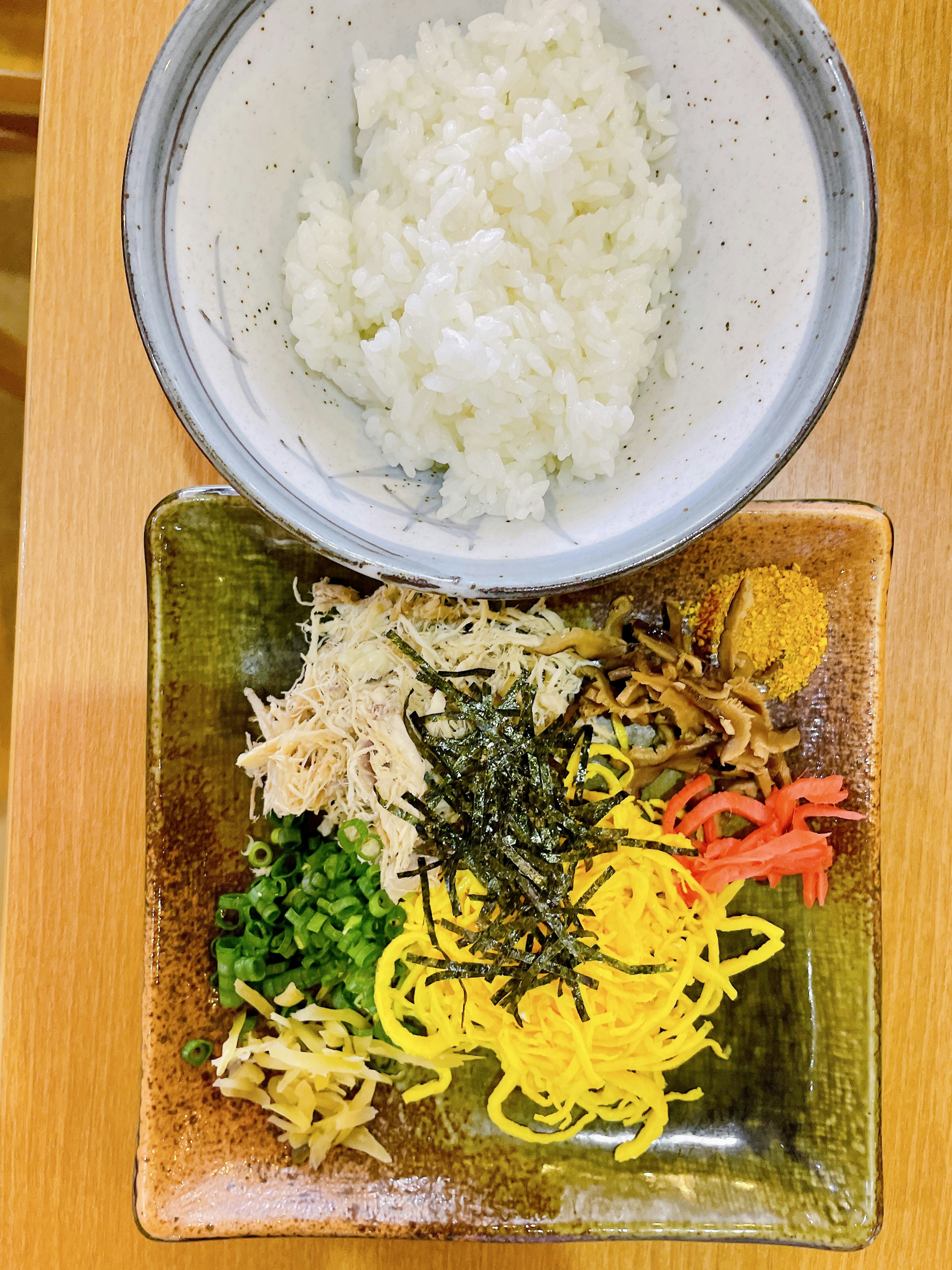 Bol de riz blanc à côté d'un assortiment coloré d'ingrédients disposés sur une assiette