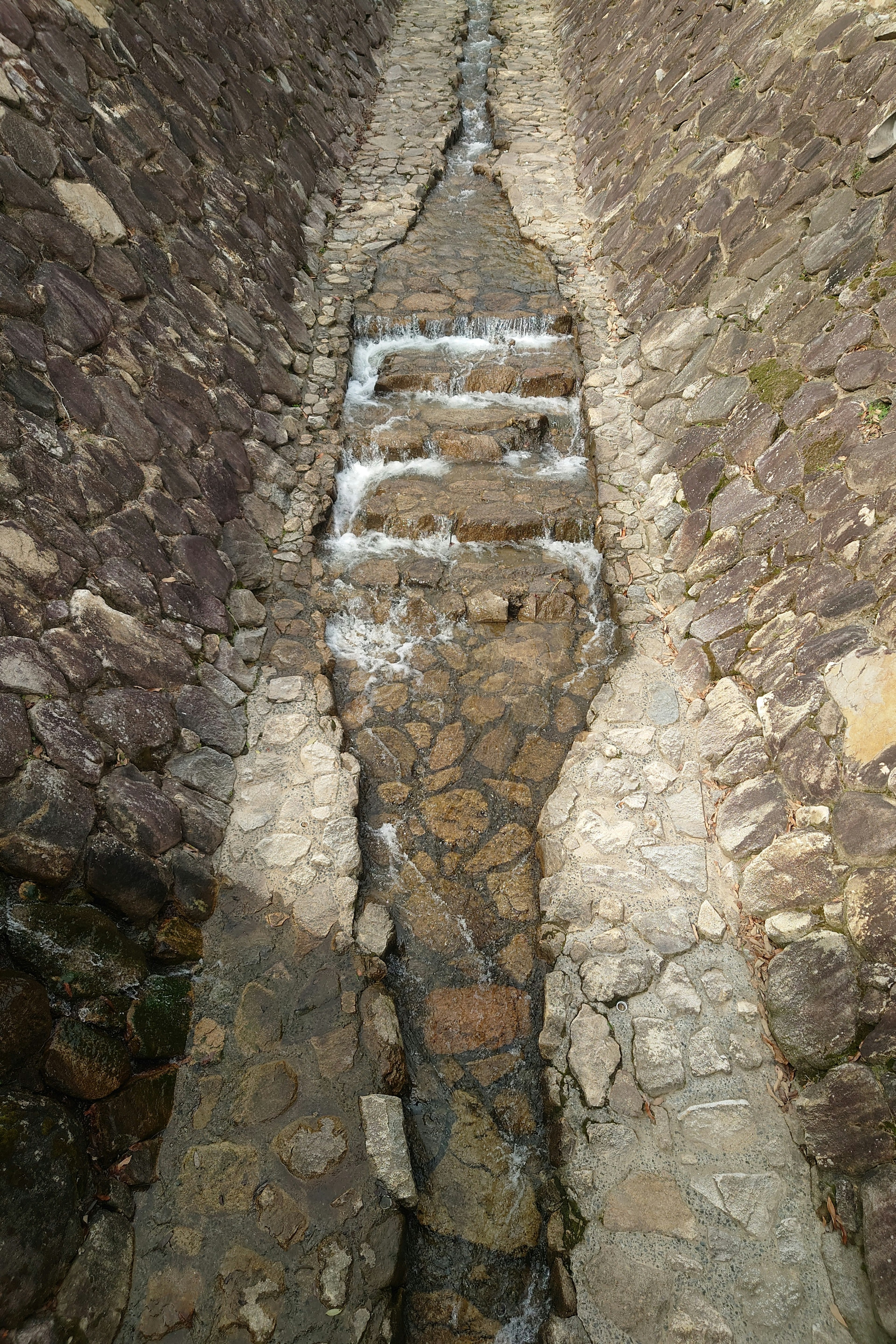 Canale in pietra con acqua che scorre e design a gradini