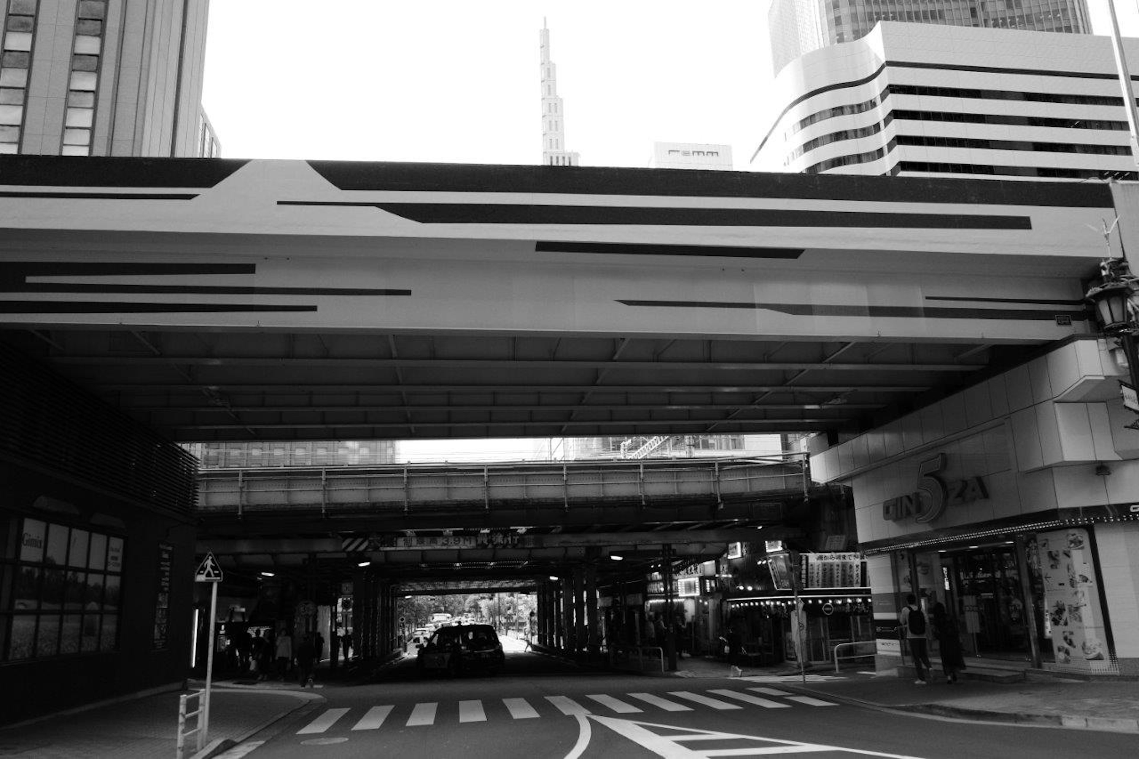 Paysage urbain en noir et blanc présentant un passage supérieur et une intersection avec des bâtiments modernes