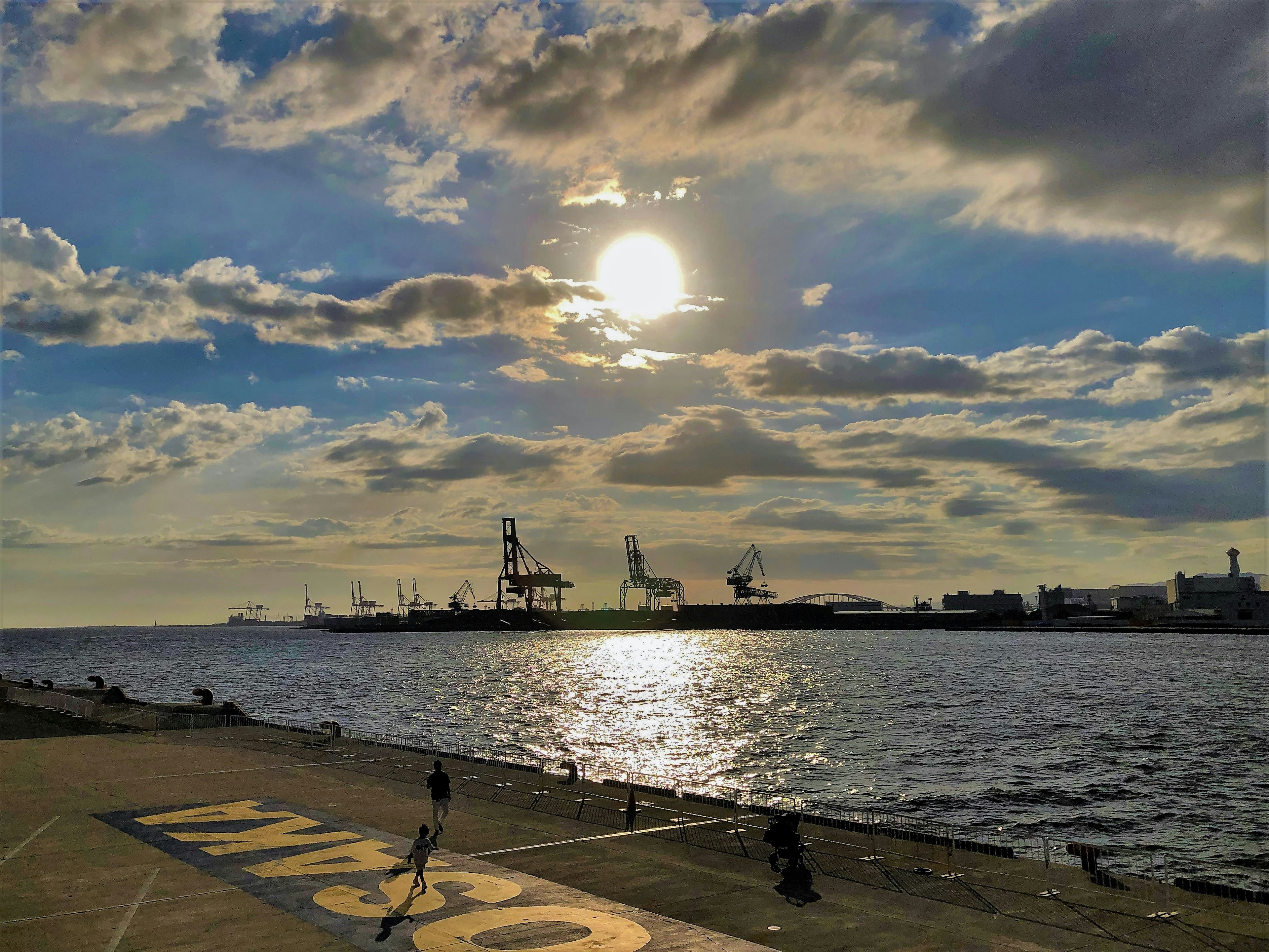 Tramonto sul porto con gru e mare calmo