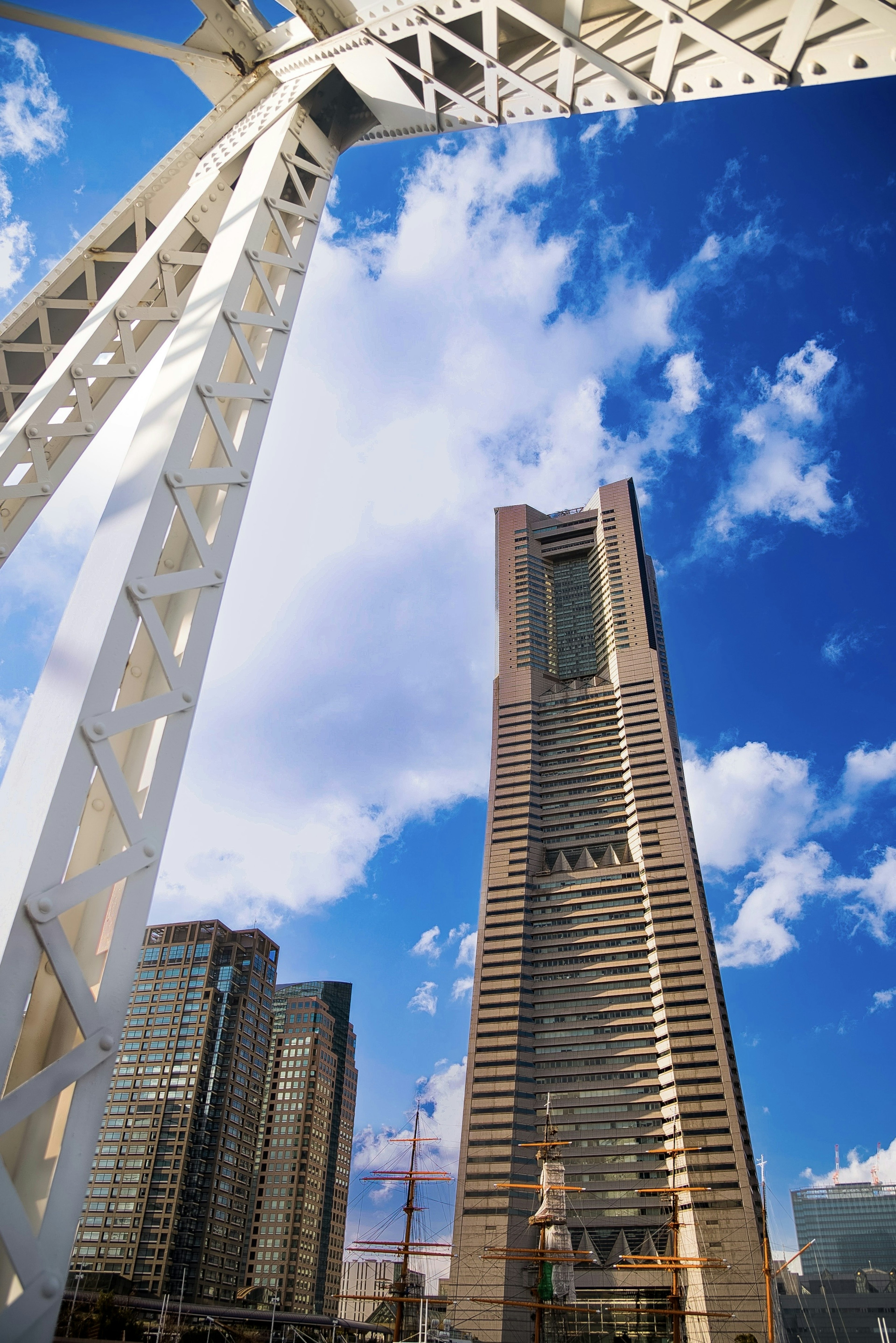 View of a skyscraper with blue sky and clouds white structure in the foreground