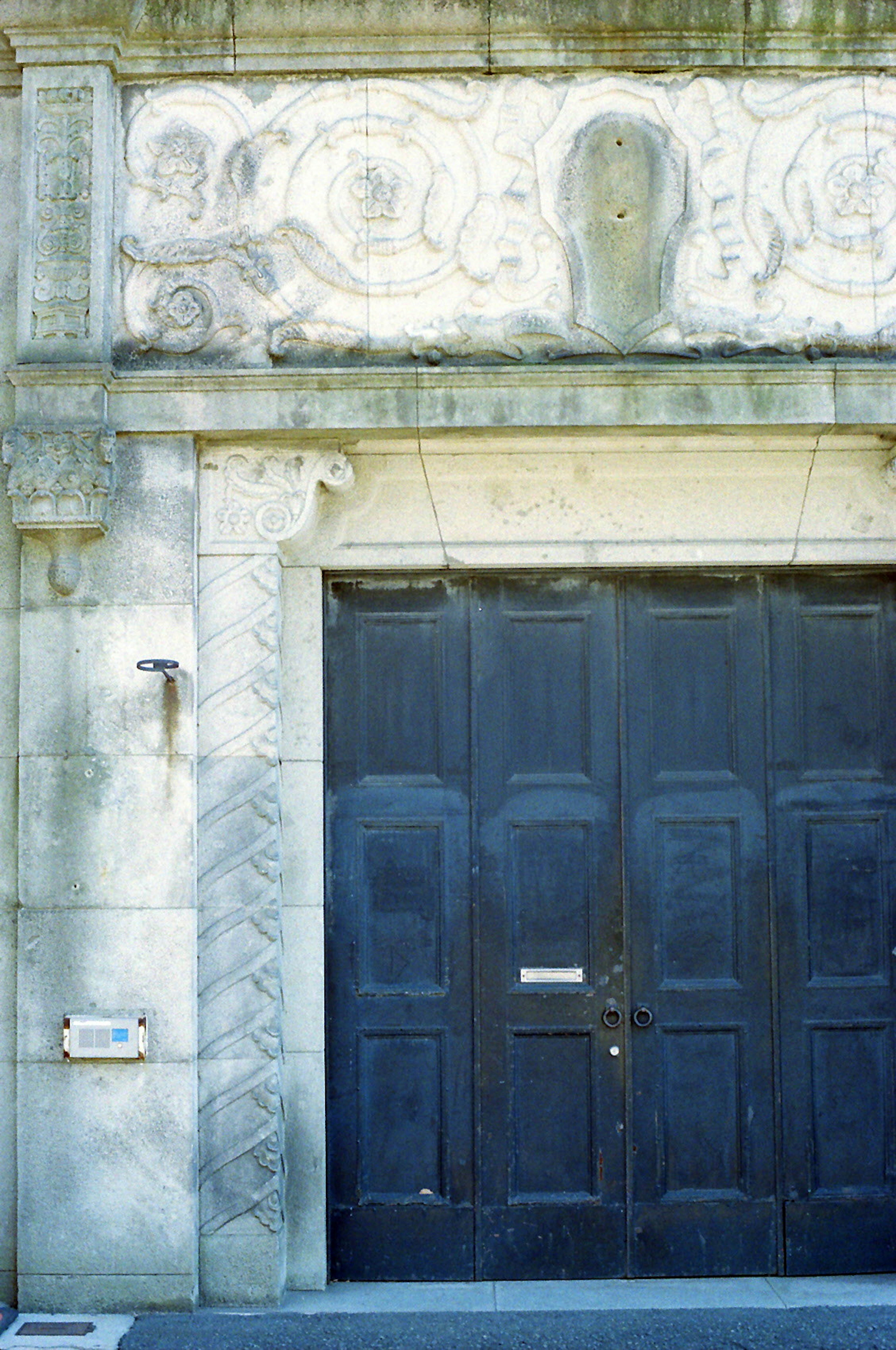 Muro in pietra decorativo con intricate sculture e una grande porta in legno nero