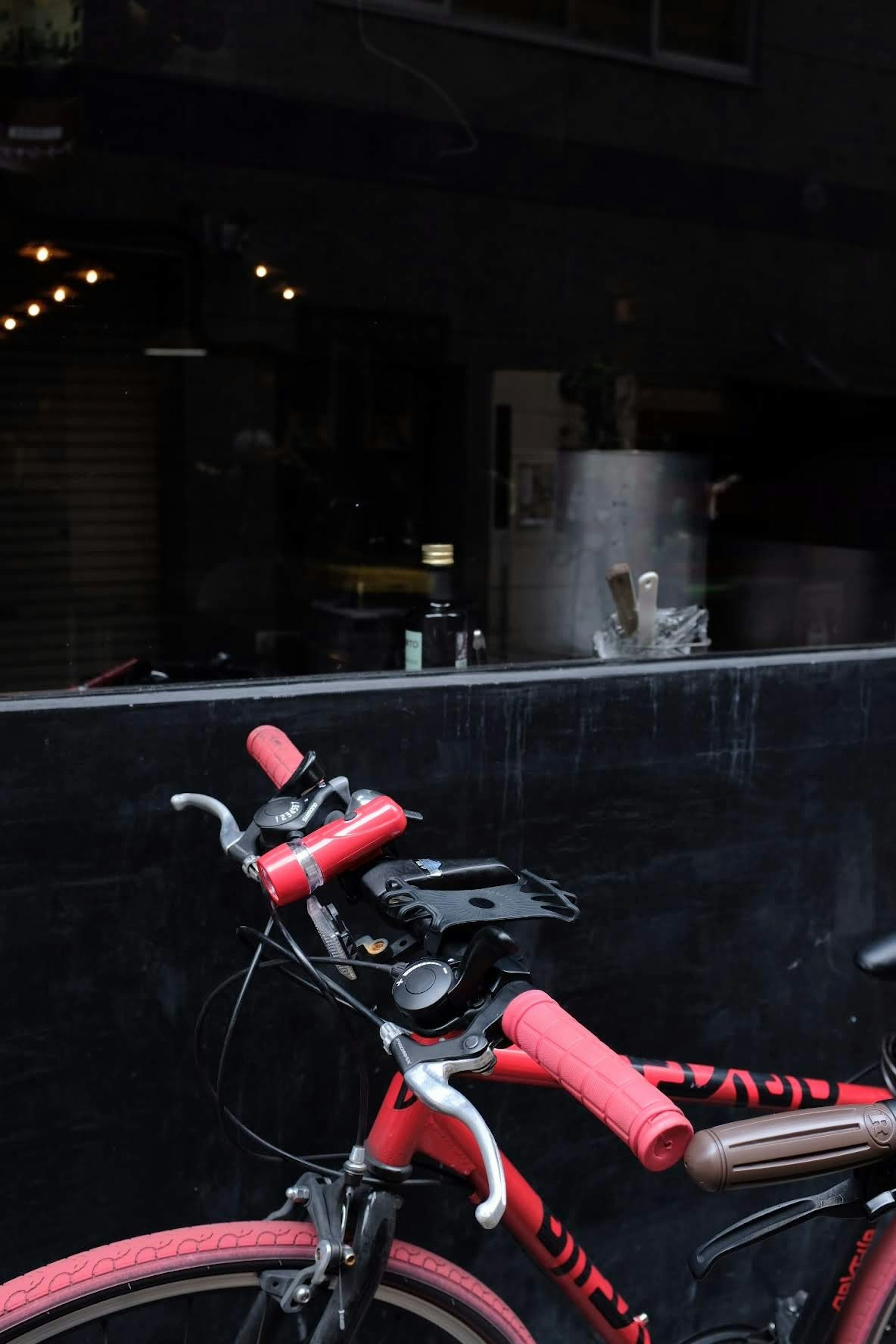 Bicicleta con empuñaduras rojas estacionada frente a una pared negra