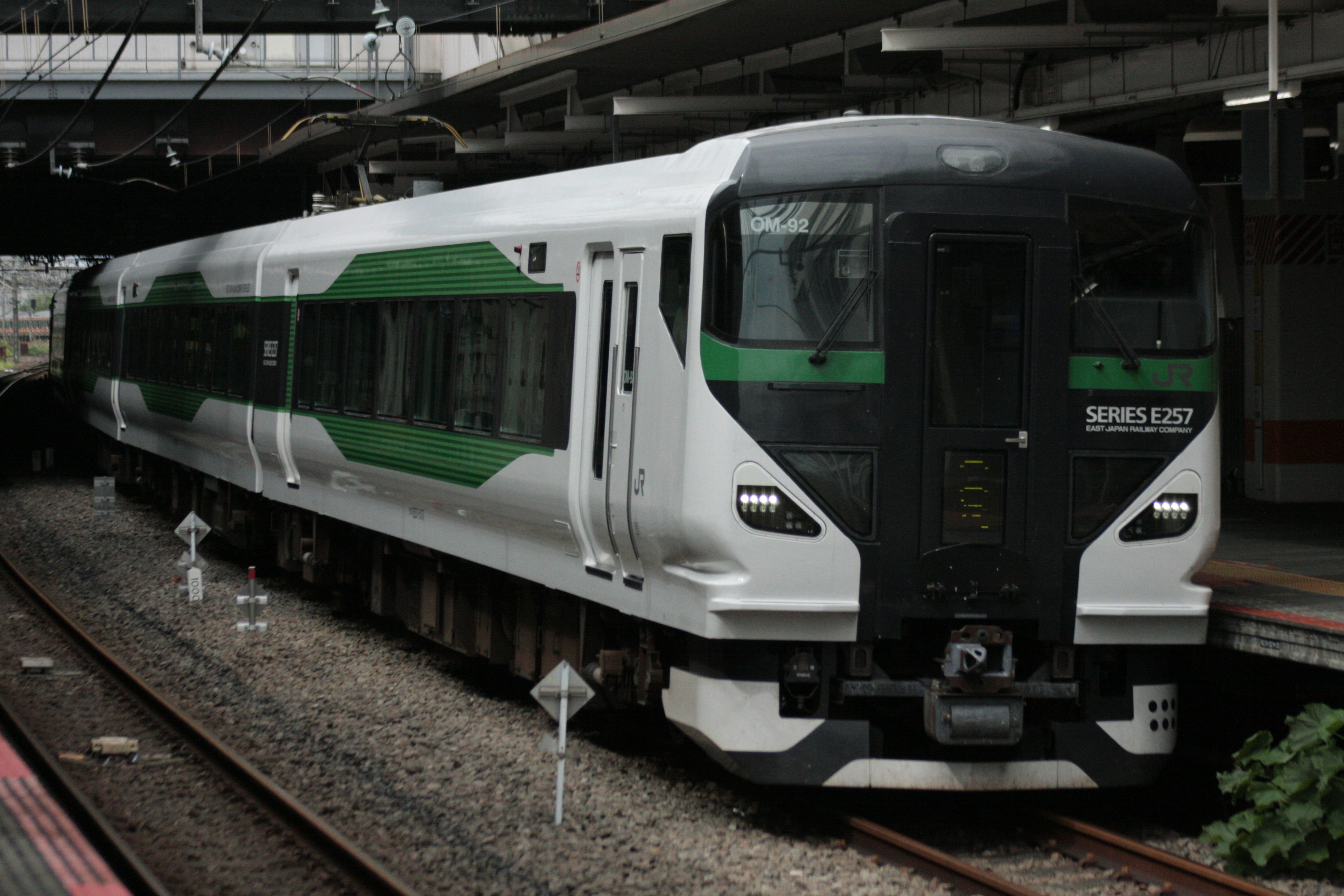 A modern train at a station with a sleek design and green accents