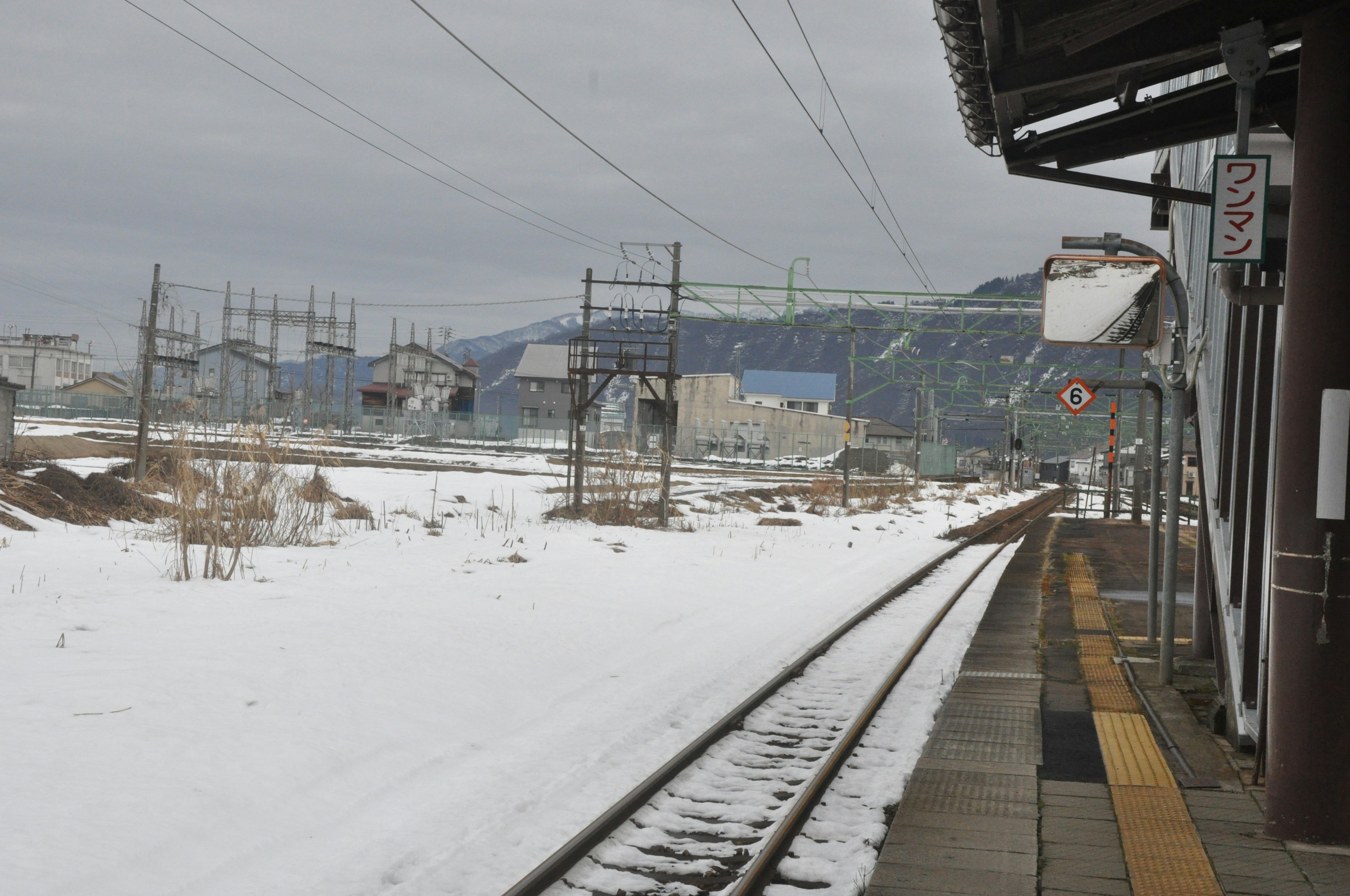 Binari e paesaggio visti da una piattaforma di stazione innevata