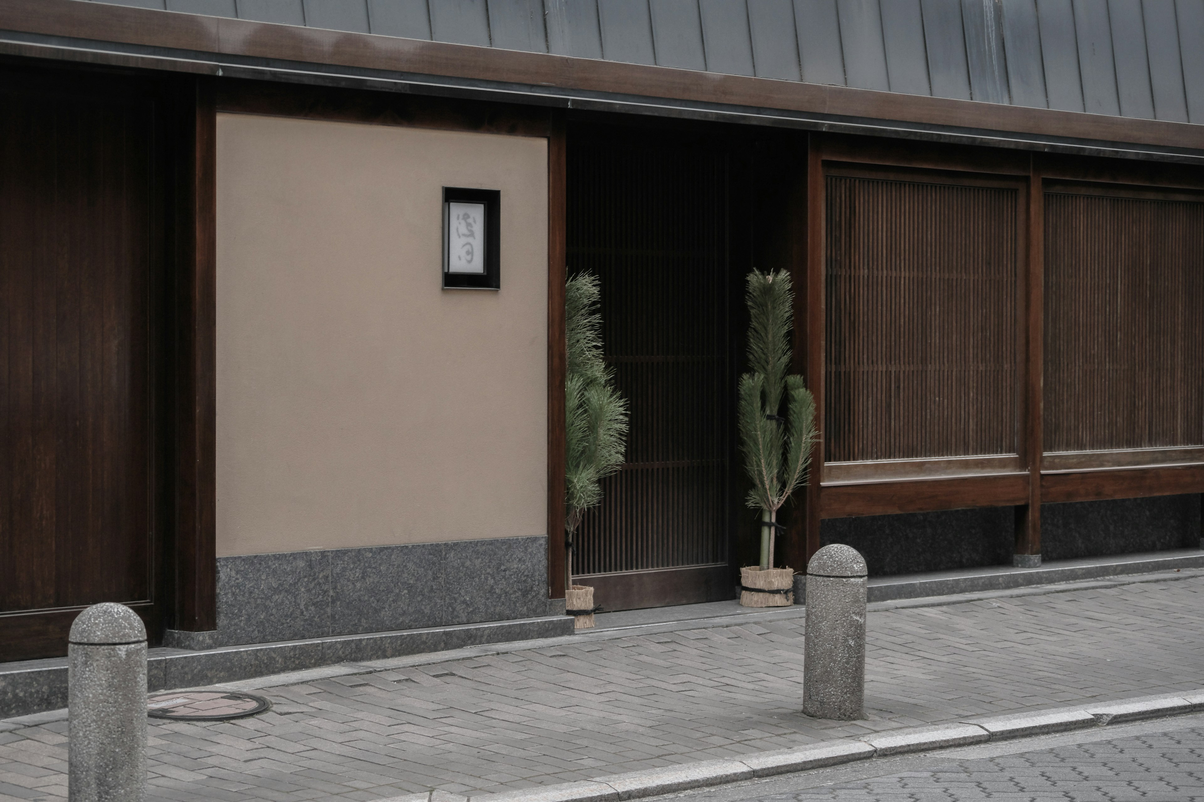 Entrance of a traditional Japanese building featuring wooden walls and greenery