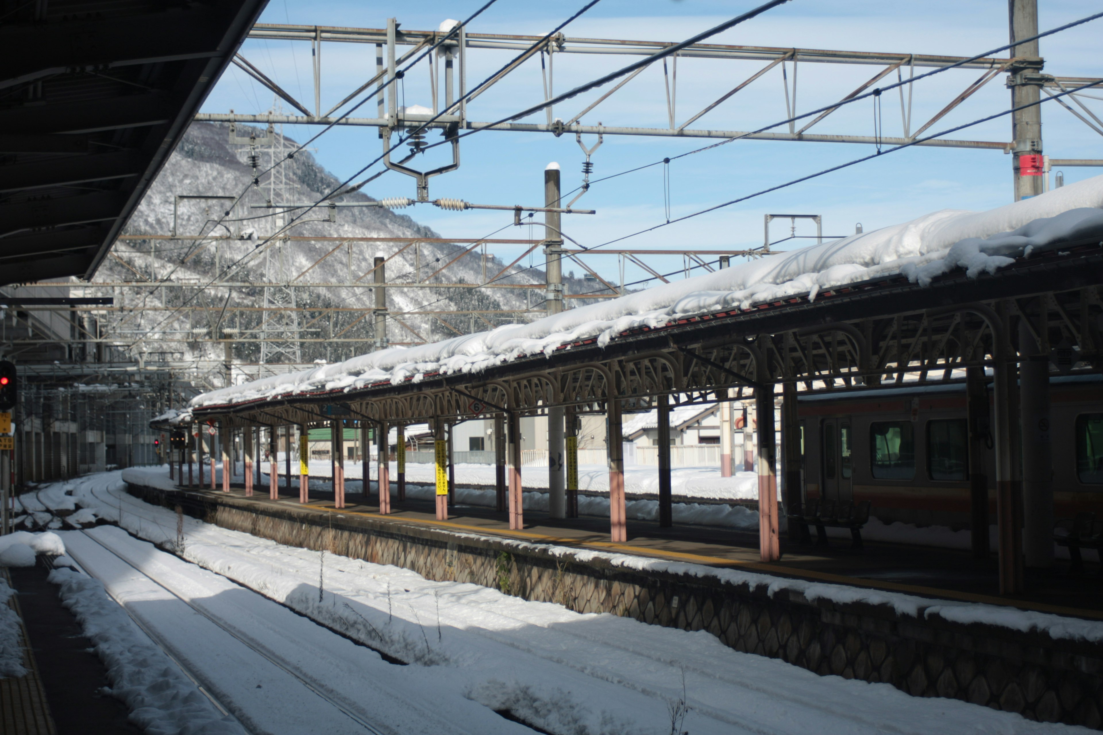 Snow-covered train station platform with mountain backdrop