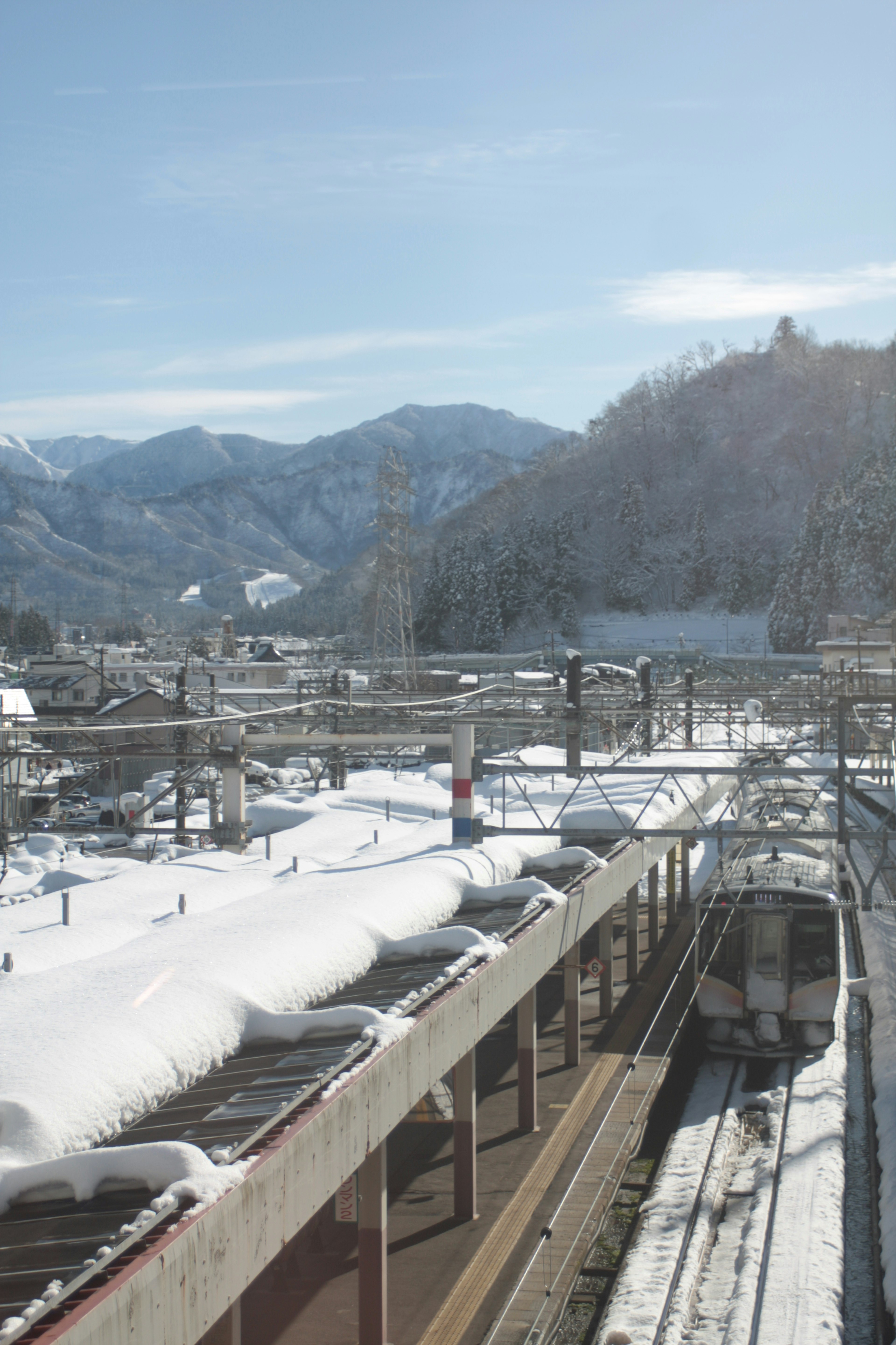 Schneebedeckter Bahnhof mit Bergen im Hintergrund