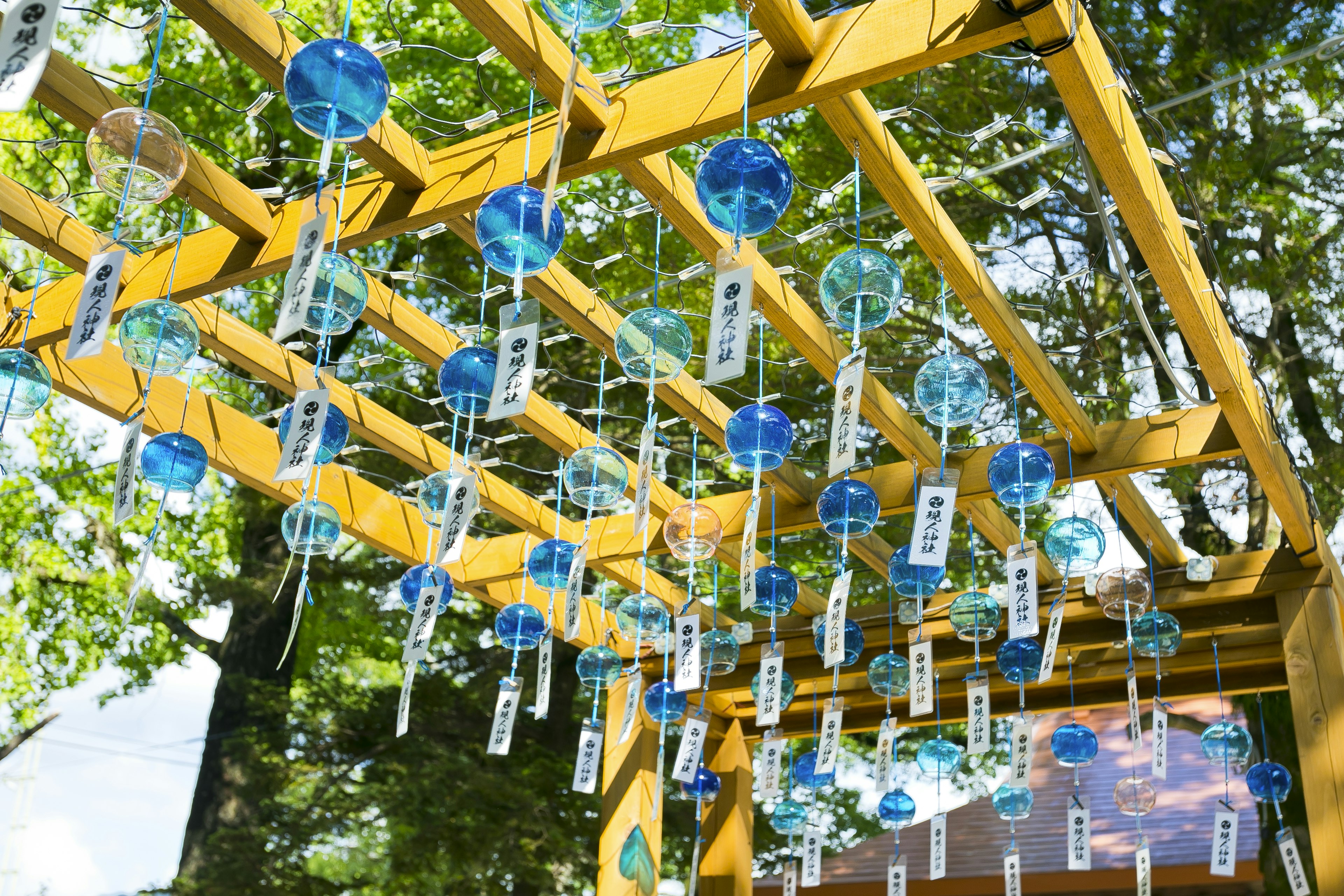 Blaue Windspiele hängen von einer gelben Holzstruktur