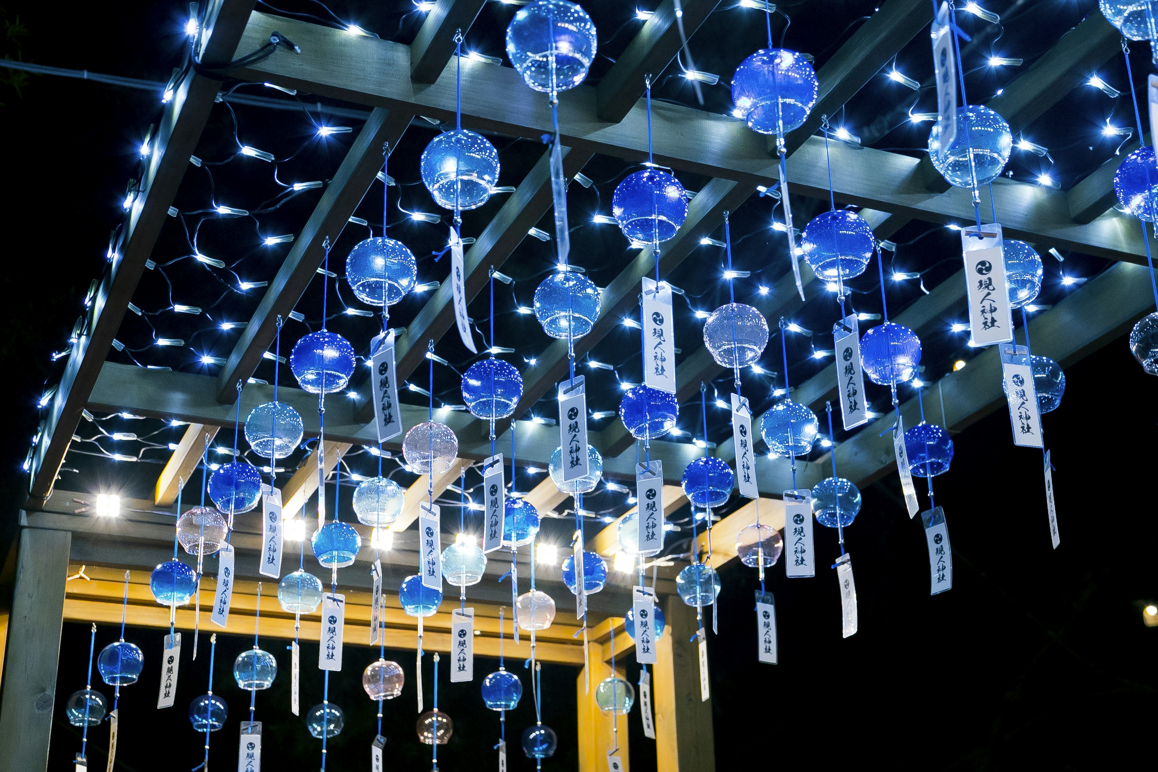 Night view with blue wind chimes hanging under a lit roof