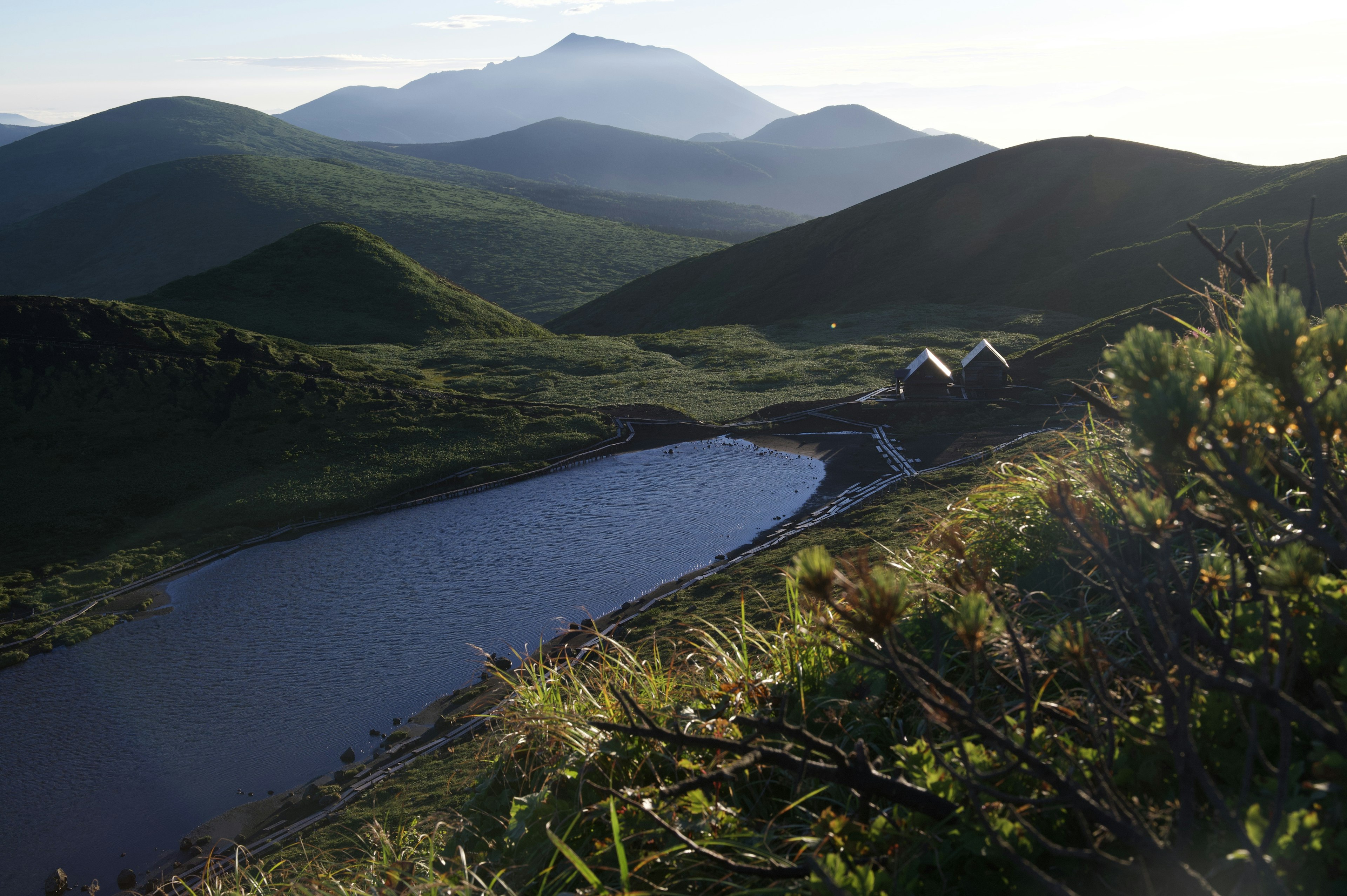 Vue panoramique de montagnes verdoyantes et d'un lac tranquille avec des maisons à proximité