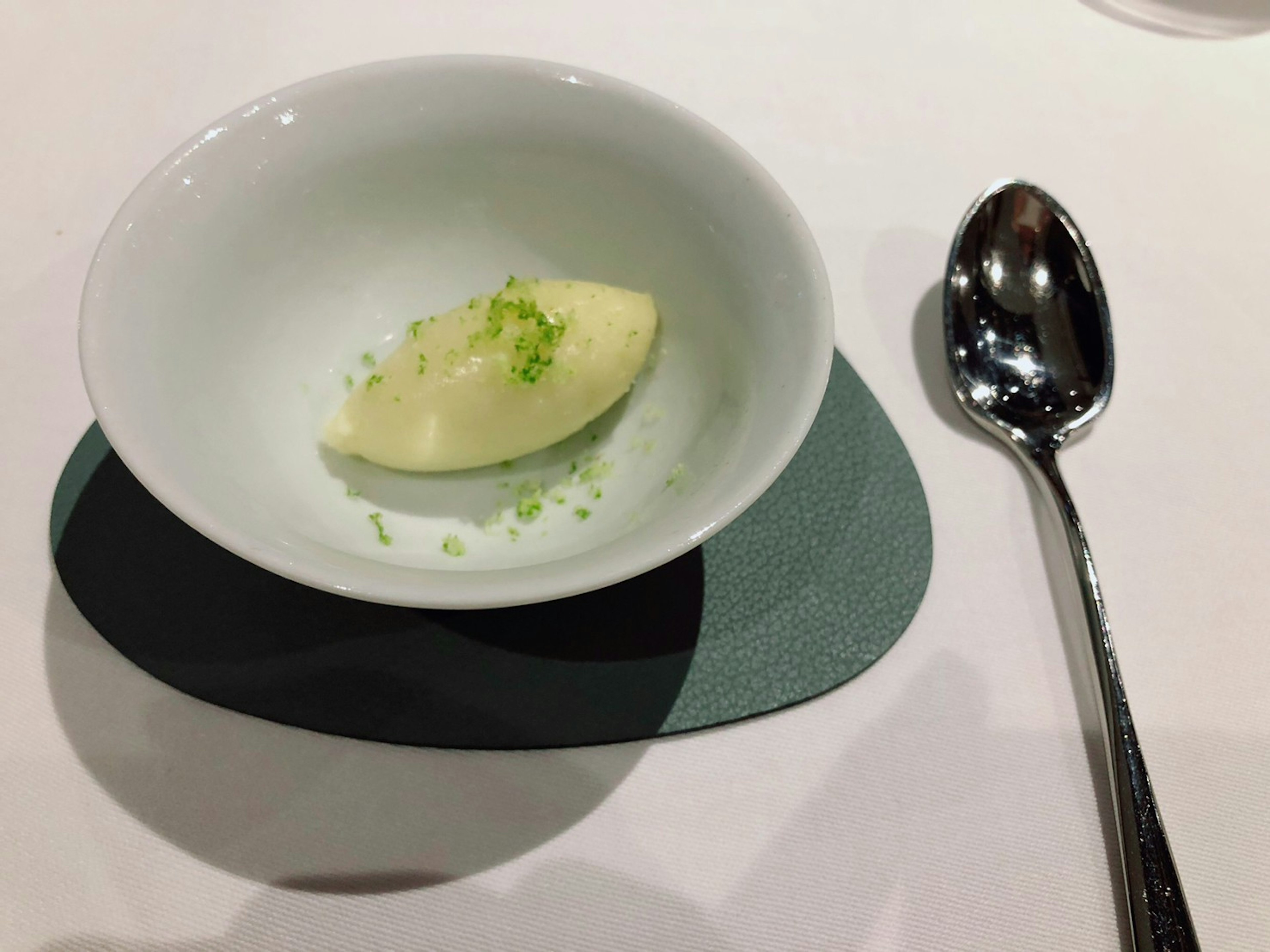 Lemon-flavored sorbet served in a white bowl with lime zest on top