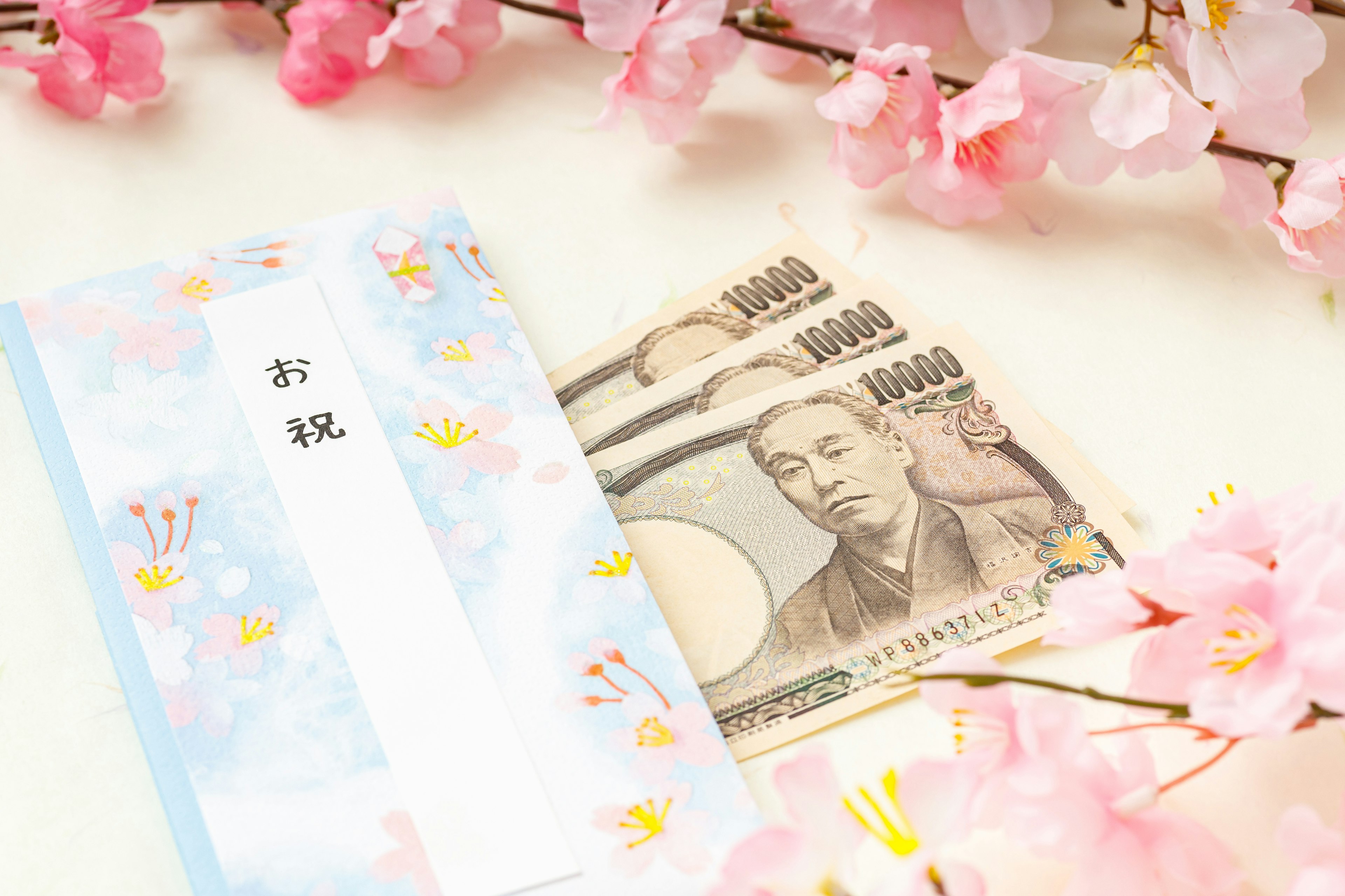 Money and a congratulatory envelope placed on cherry blossom petals