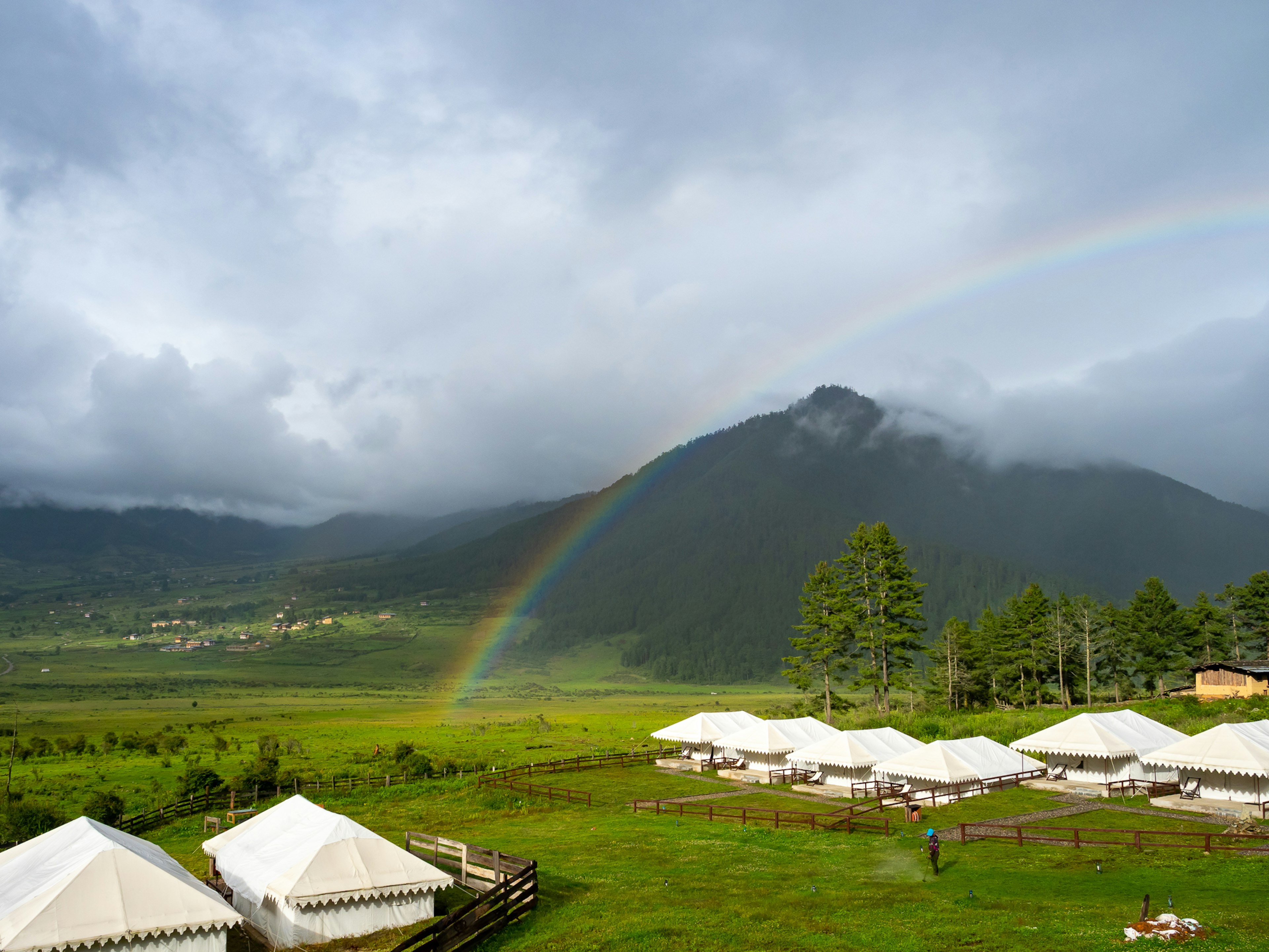 Malersiche Aussicht mit weißen Zelten und einem Regenbogen über Bergen