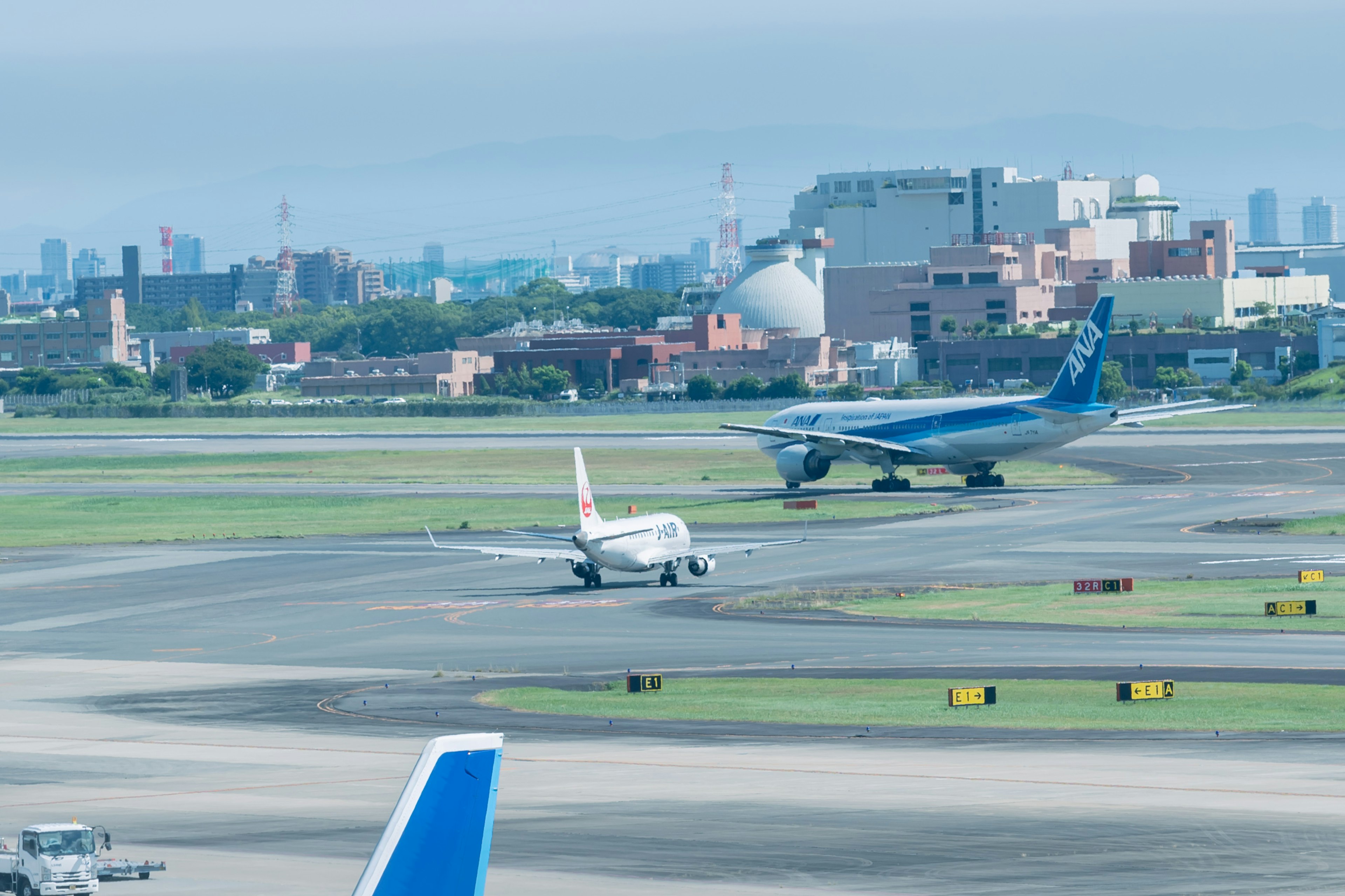 Airplanes on an airport runway with a city skyline in the background