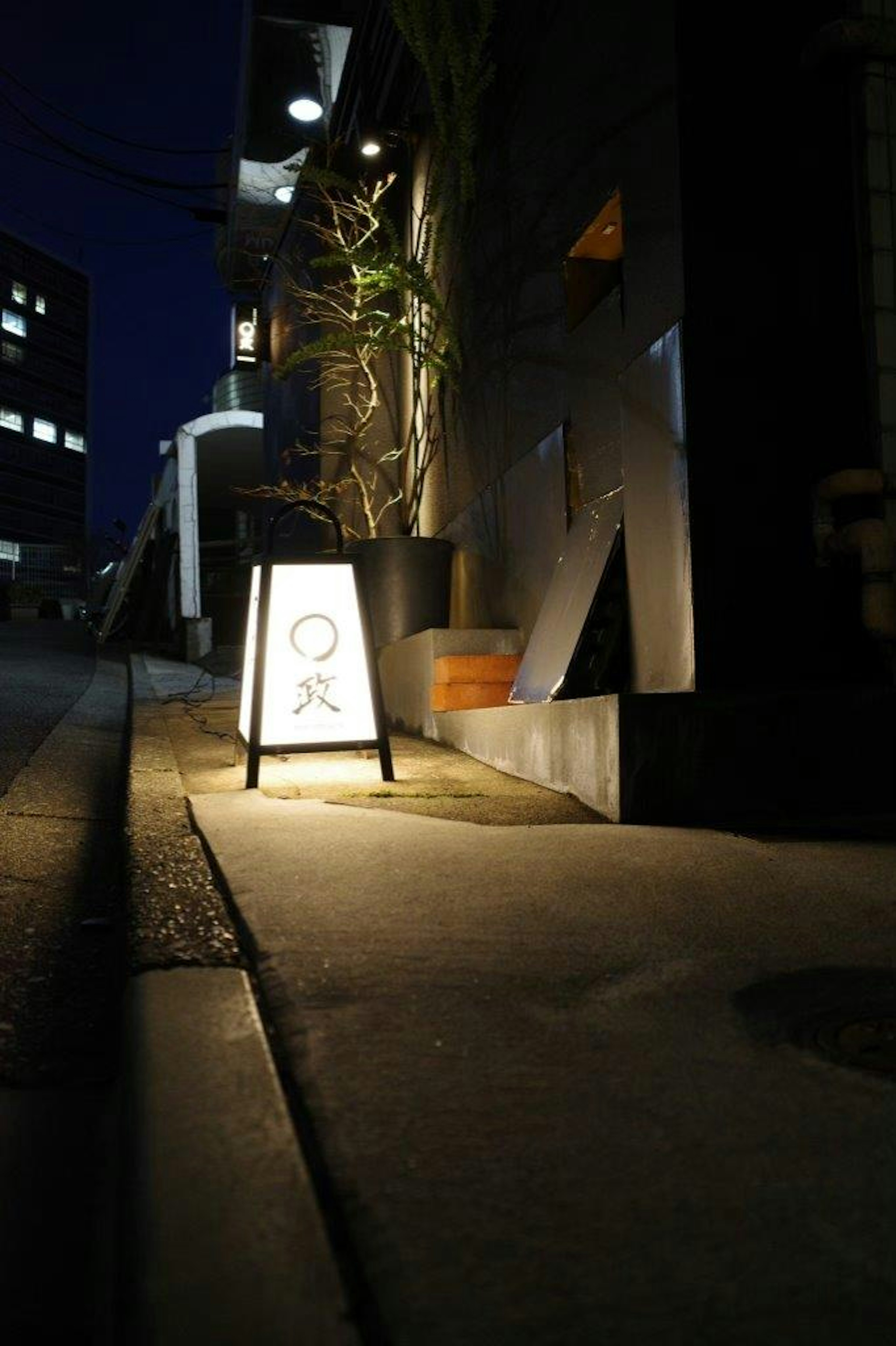 Beleuchtetes Schild auf einem Bürgersteig bei Nacht mit urbanem Hintergrund