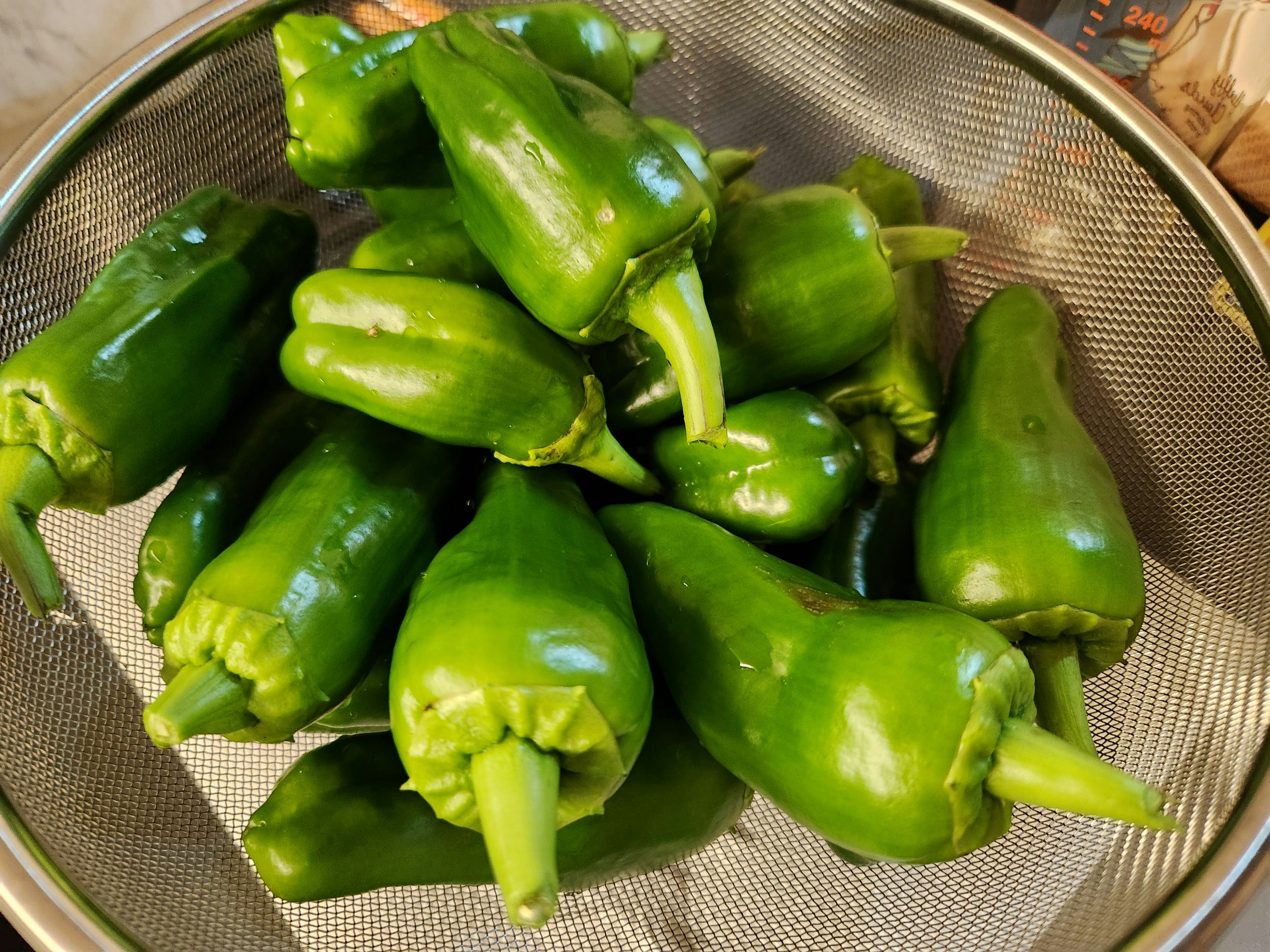 Fresh green peppers arranged in a strainer