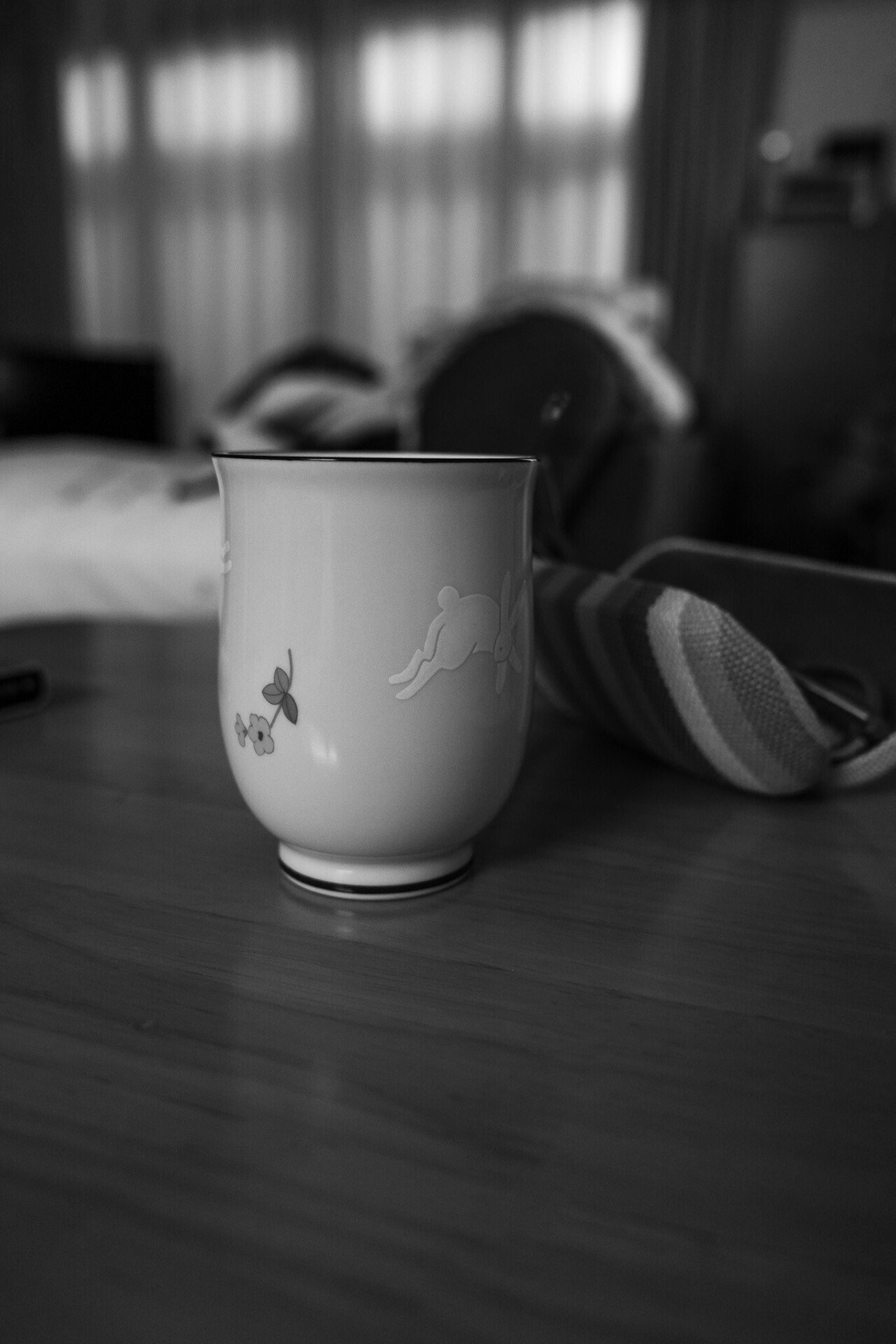 White ceramic cup with blurred furniture in the background in black and white