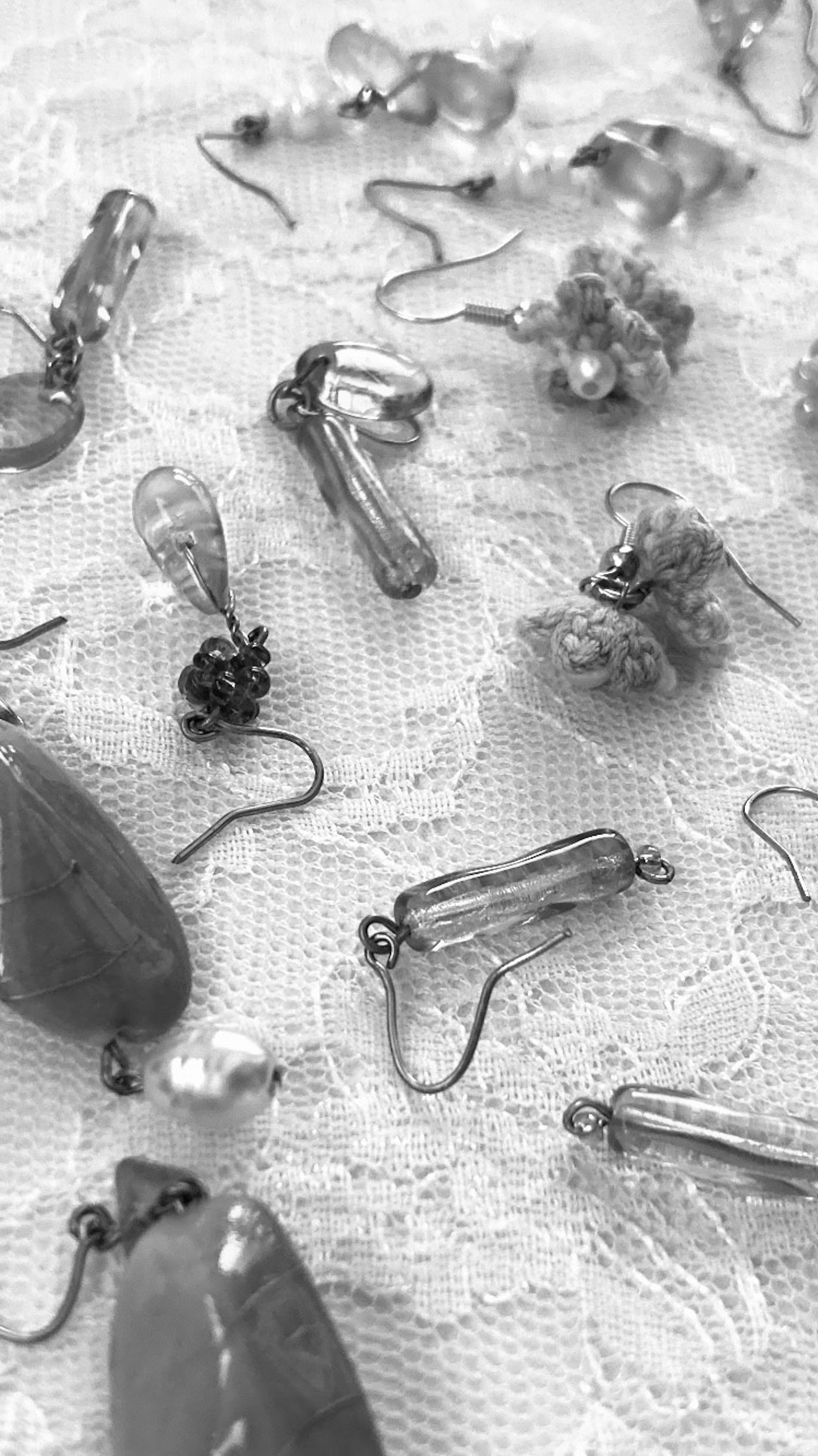 Varios aretes de cristal y cuentas transparentes esparcidos sobre una tela de encaje