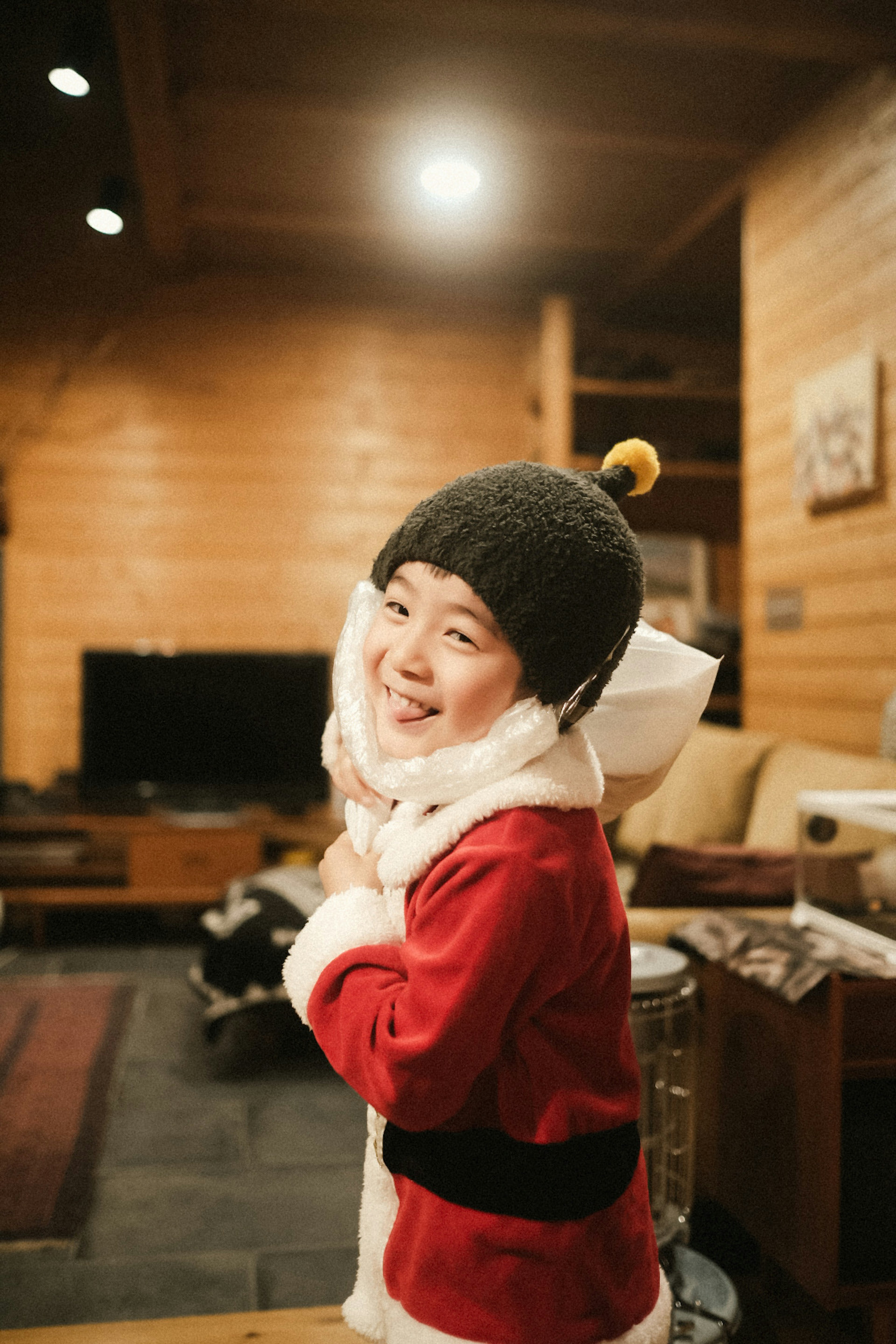 Child in a red Santa costume smiling and posing indoors