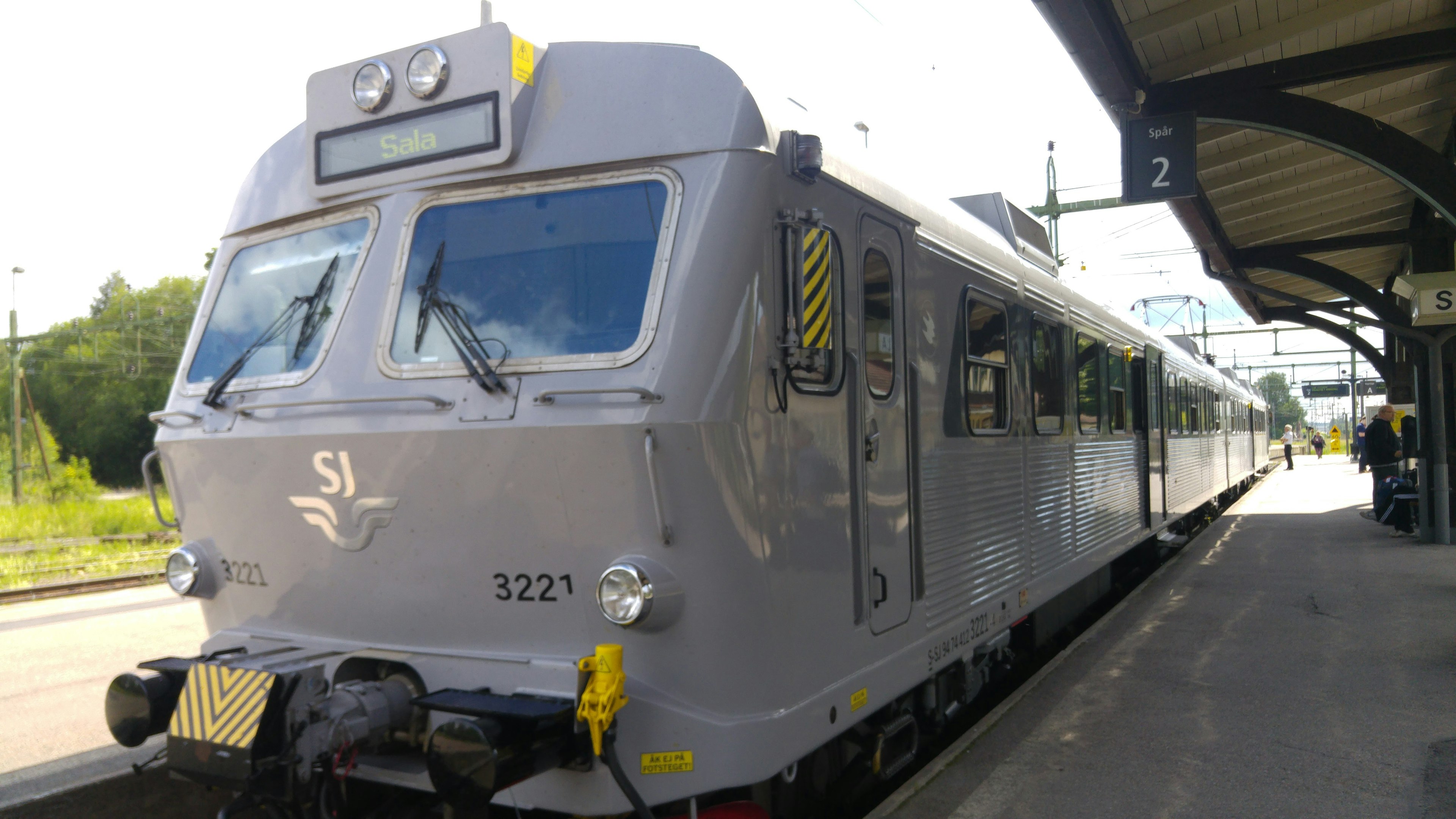 Kereta perak diparkir di stasiun dengan pemandangan sekitar