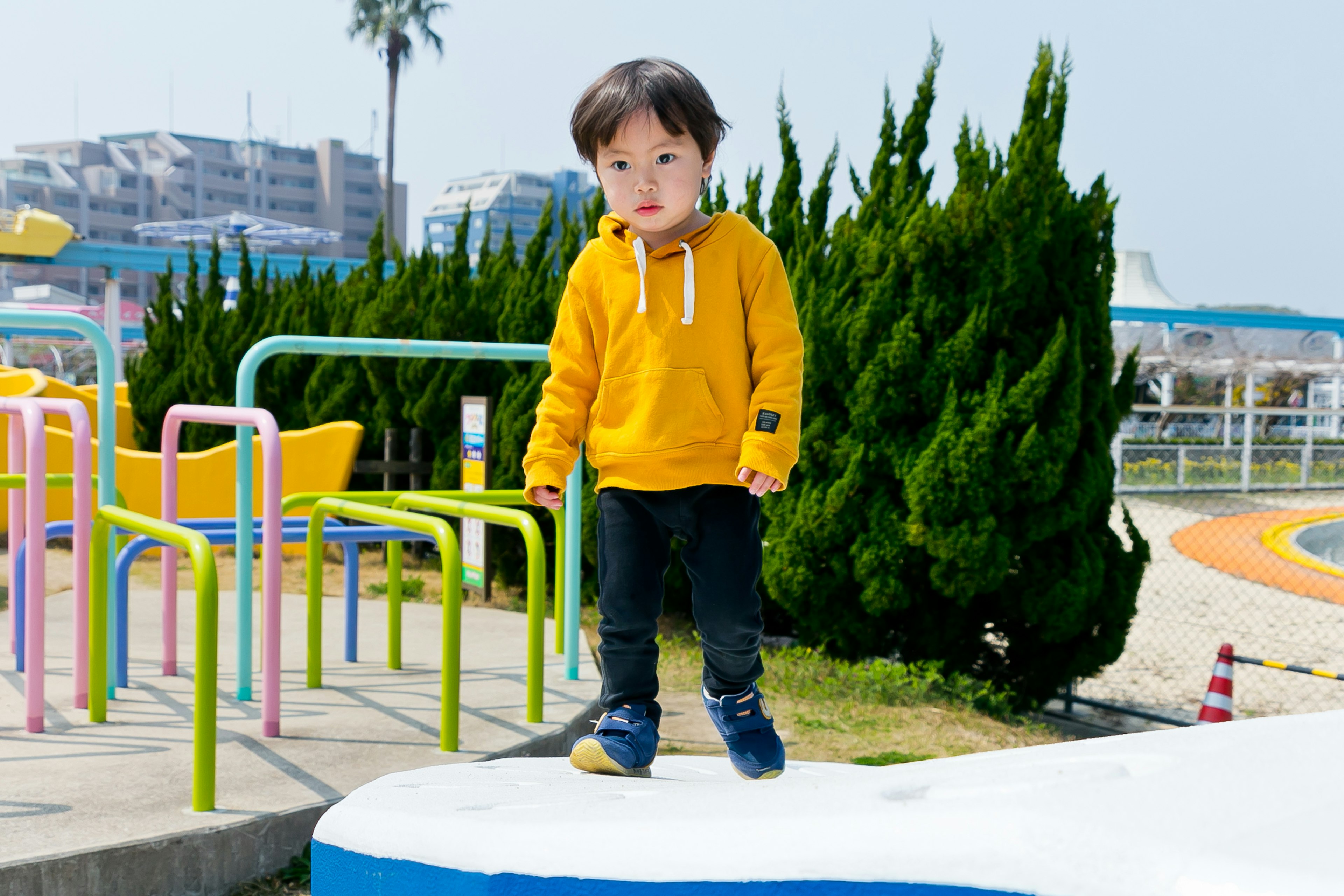 公園で黄色いフード付きパーカーを着た子供が遊んでいる