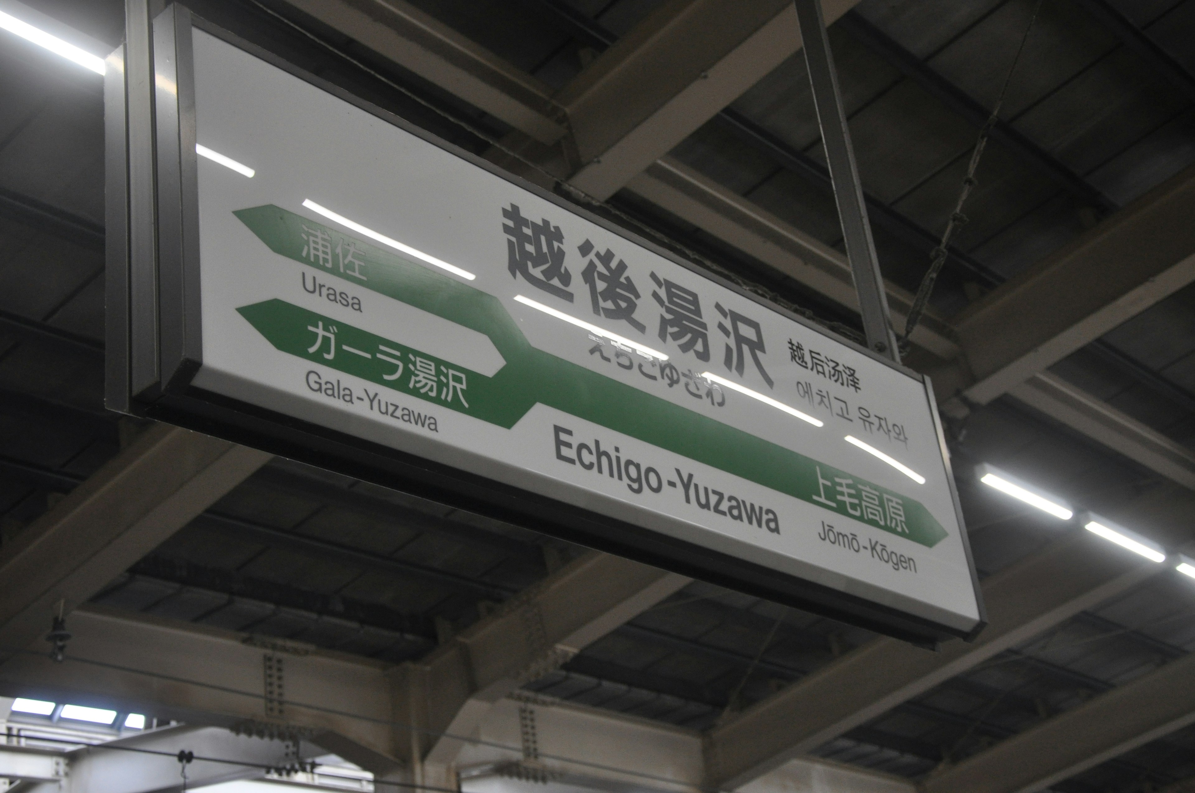 Signboard at Echigo-Yuzawa Station with directional green arrows