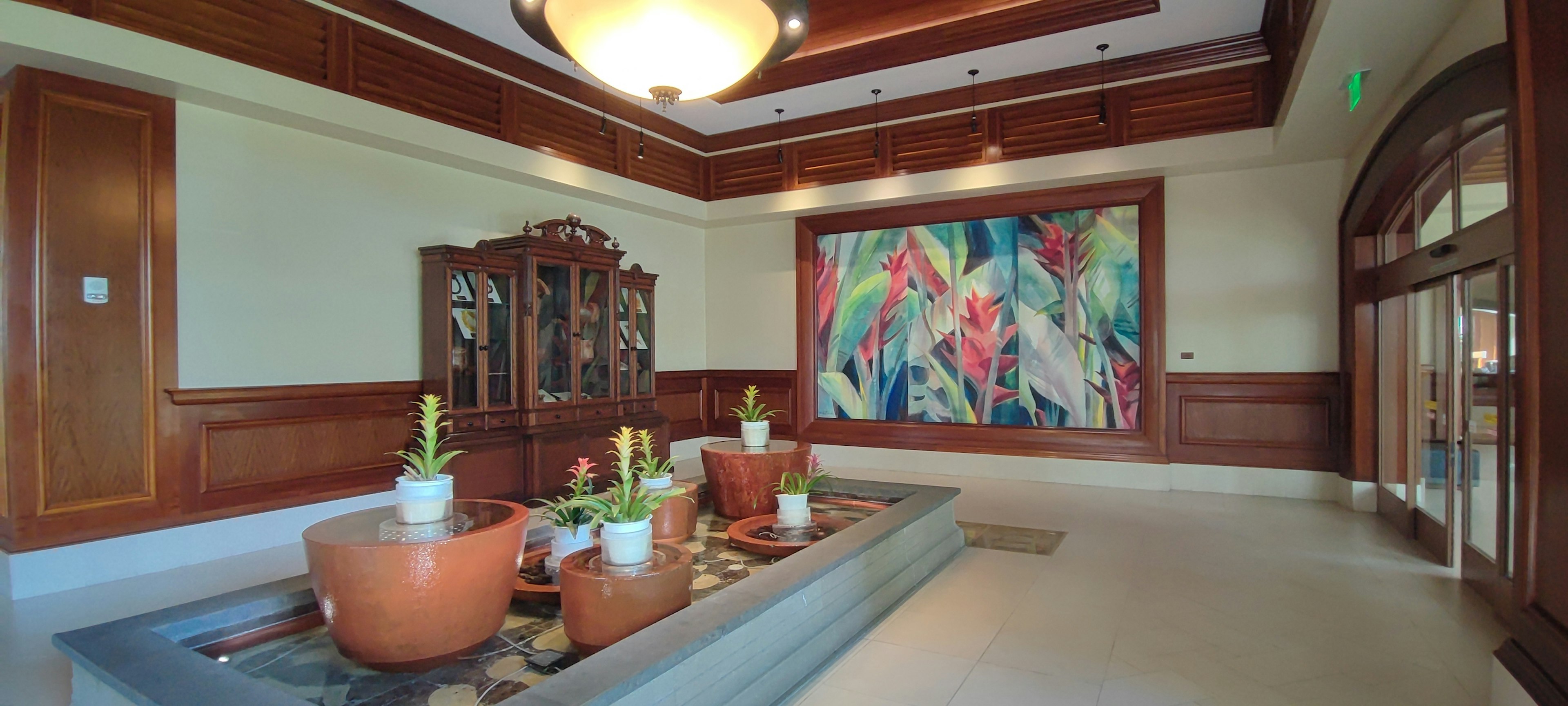 Lobby elegante con plantas en macetas y una obra de arte colorida en la pared