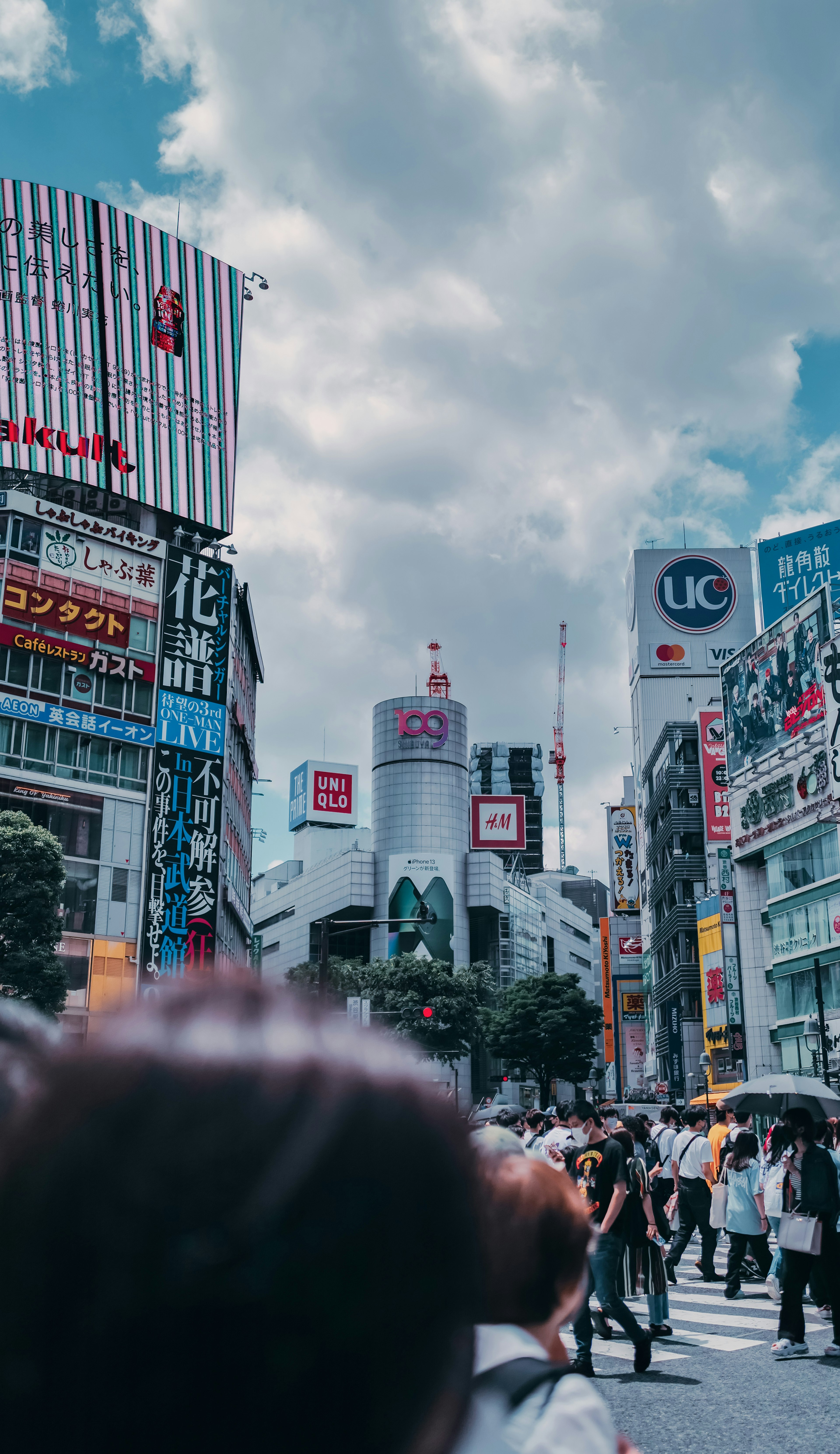 Folla all'incrocio di Shibuya con grattacieli sotto un cielo blu