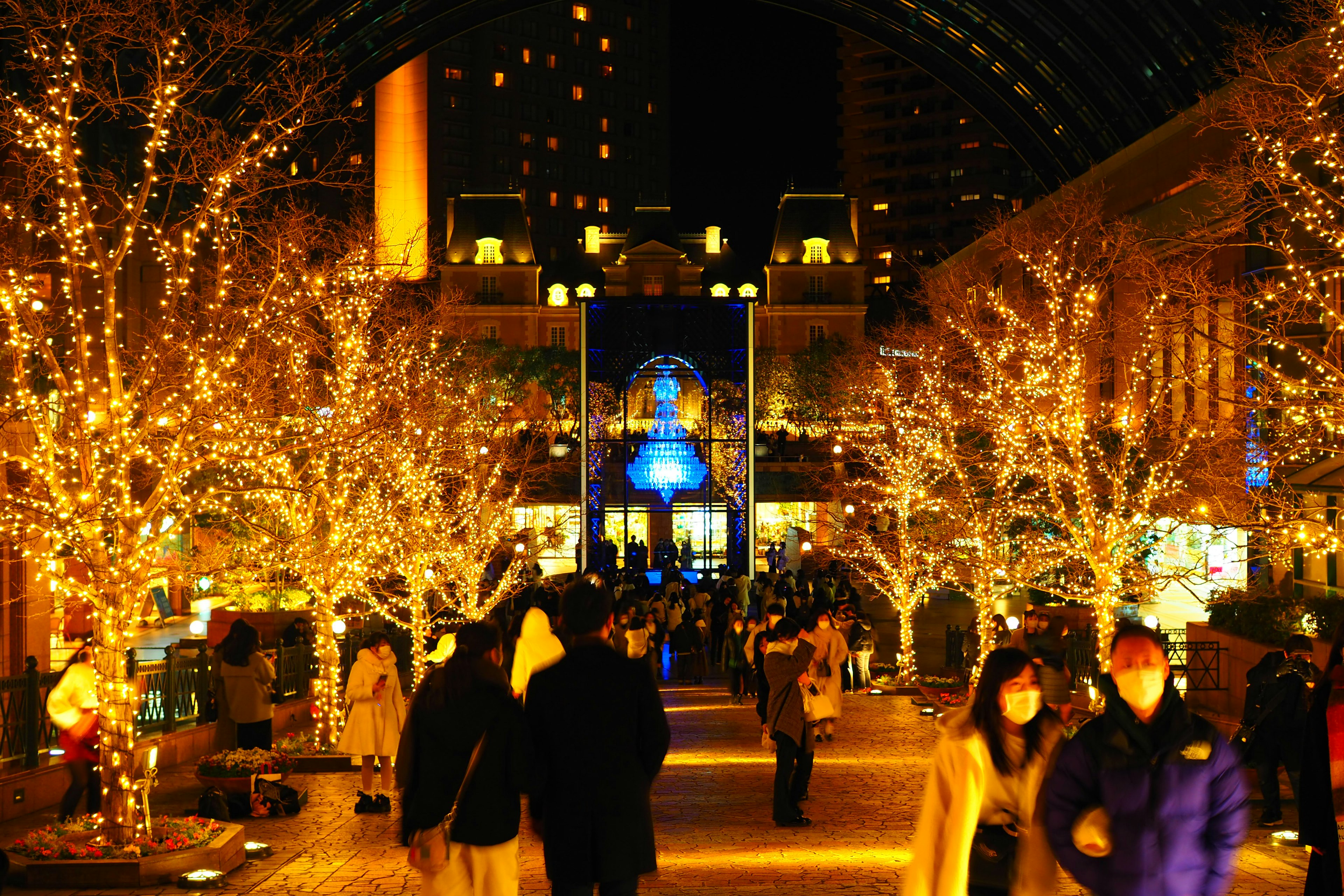 A vibrant street scene illuminated by festive lights with people walking