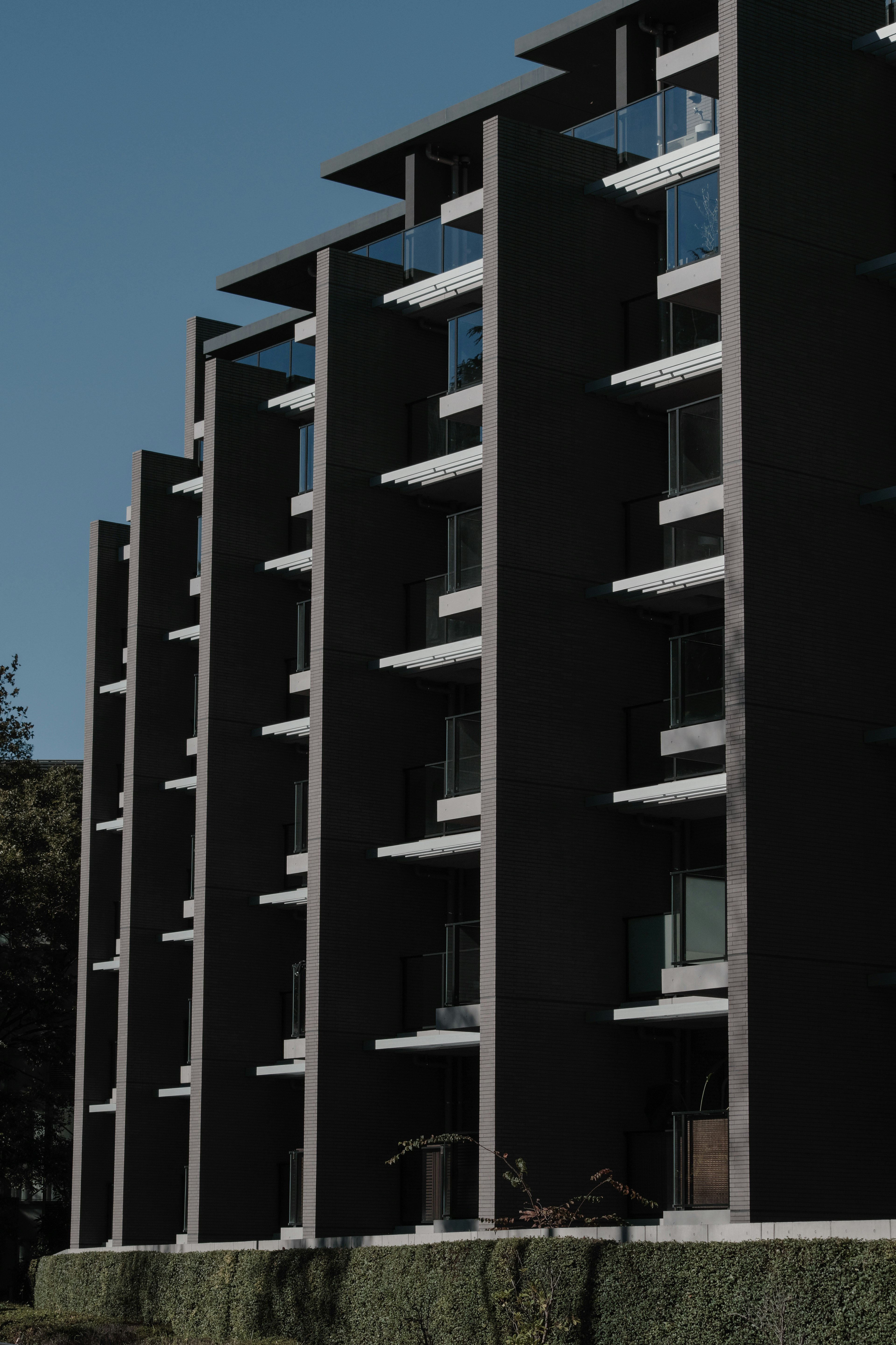 Modernes Gebäude mit schwarzen Wänden vierstöckige Struktur horizontale Fenster blauer Himmel