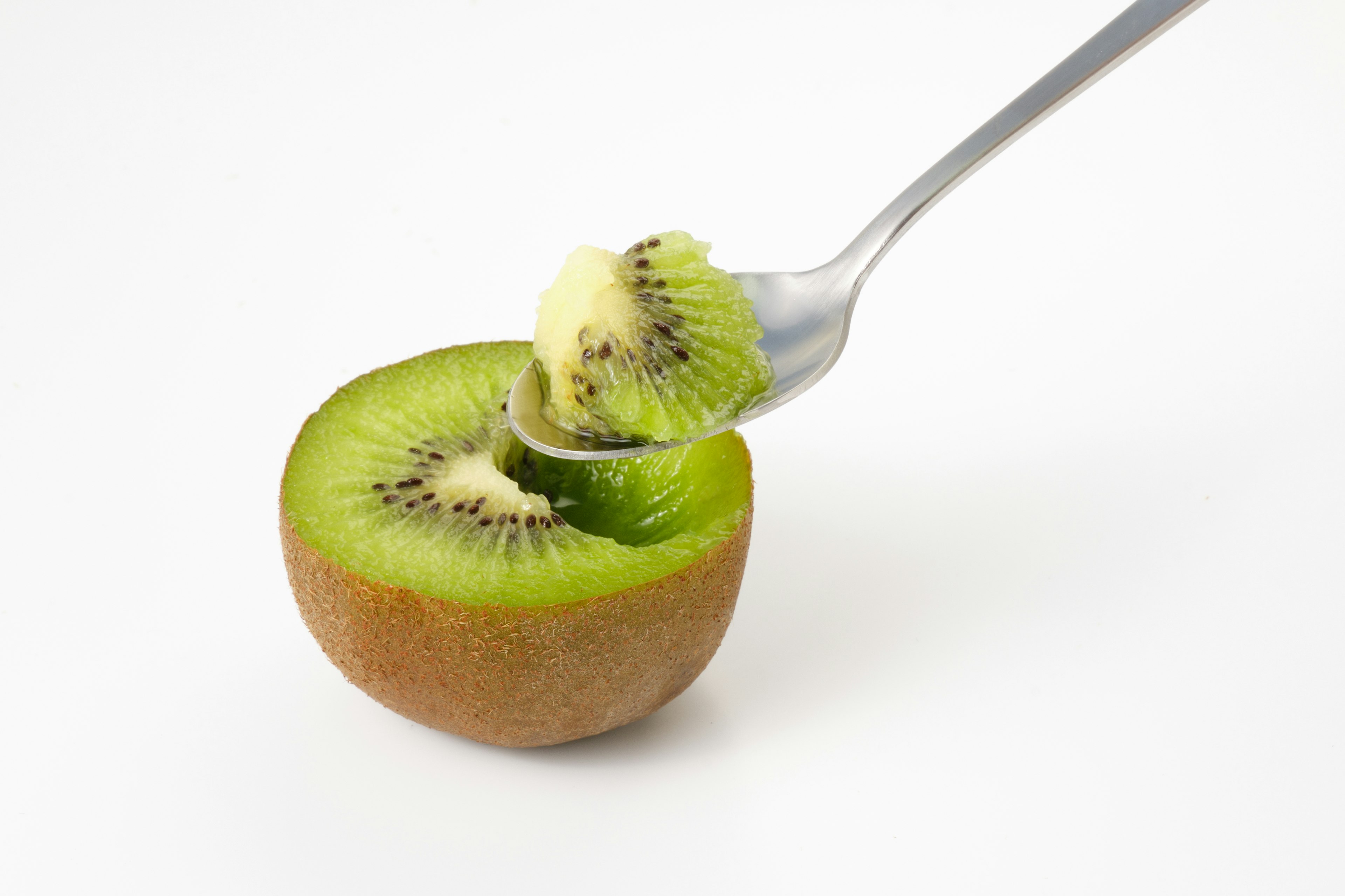 Hälfte einer Kiwi mit grünem Fruchtfleisch, die mit einer Gabel aufgenommen wird