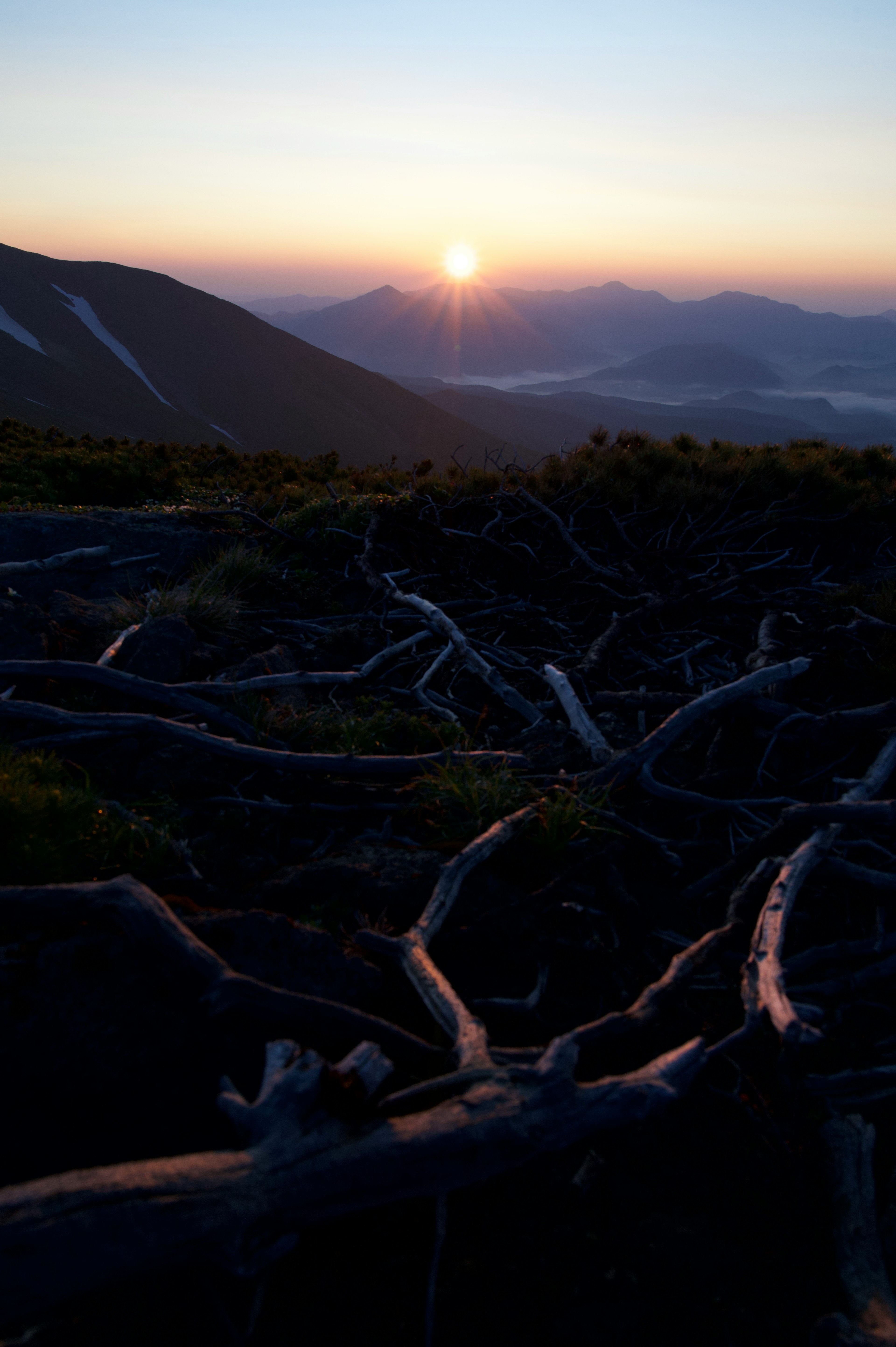 Amanecer sobre montañas con raíces de árboles expuestas en primer plano