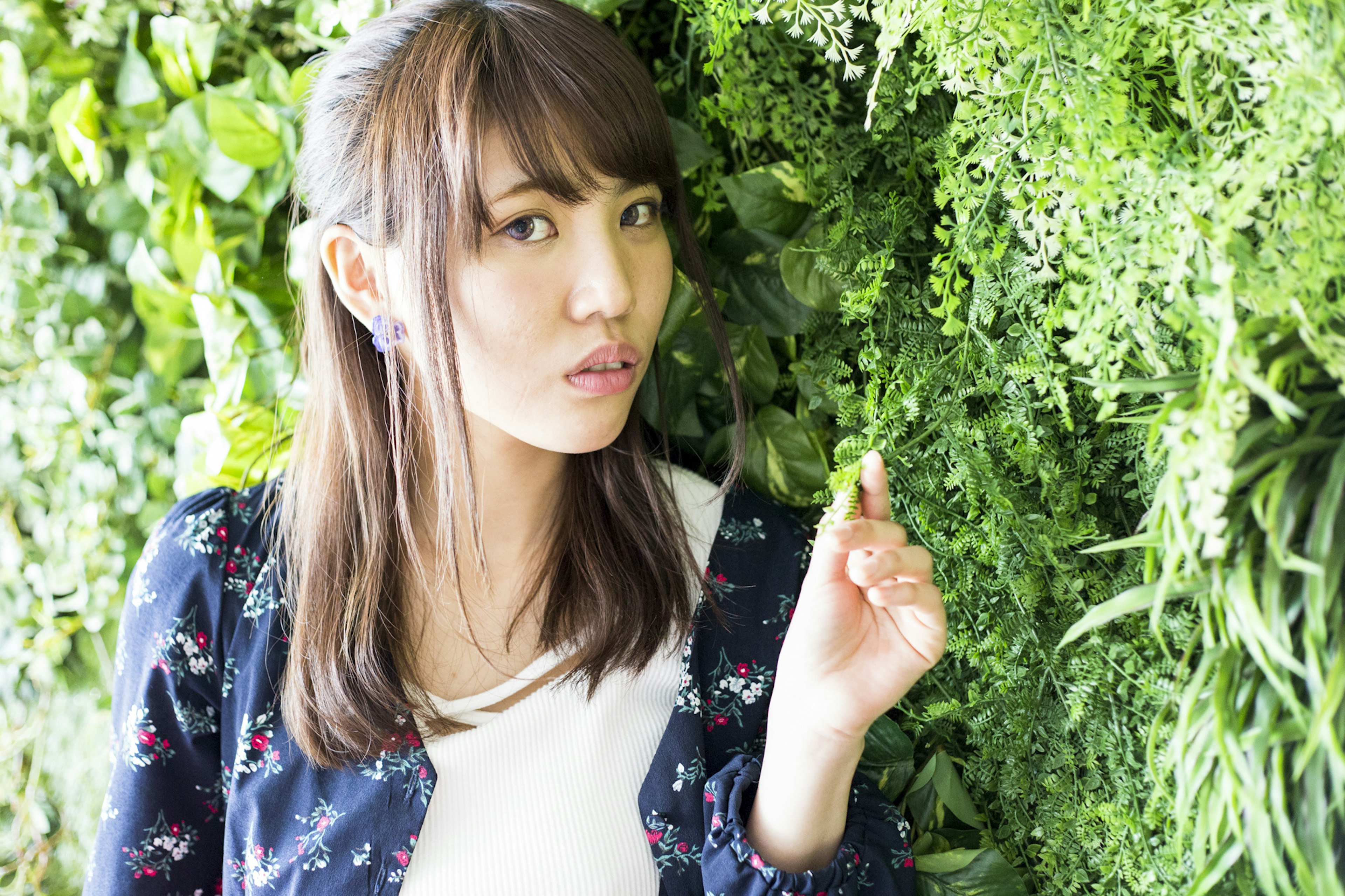 A woman standing in front of a green wall pointing at something