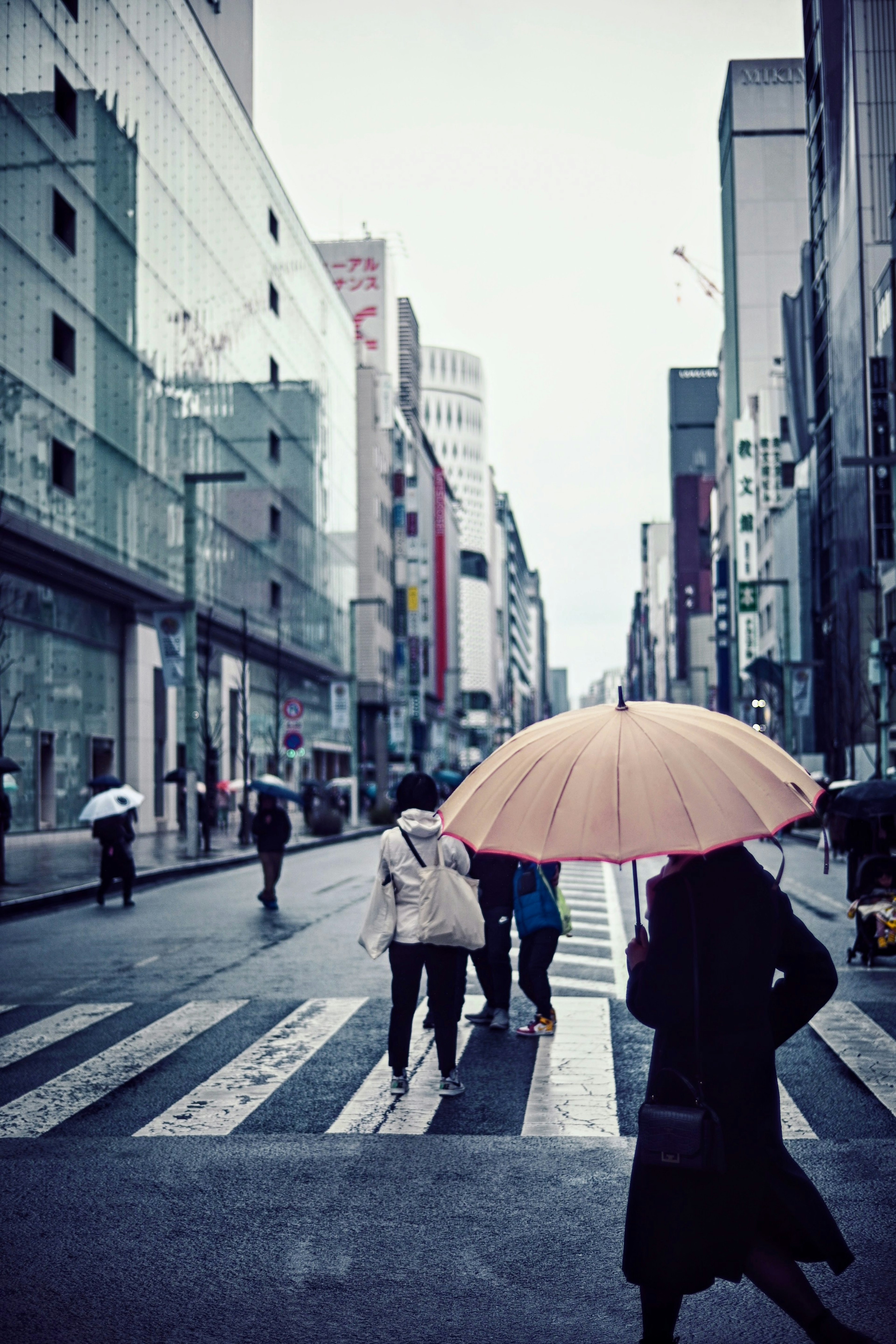 Scène de rue en ville avec des personnes traversant le passage piéton une femme avec un parapluie jaune se distingue