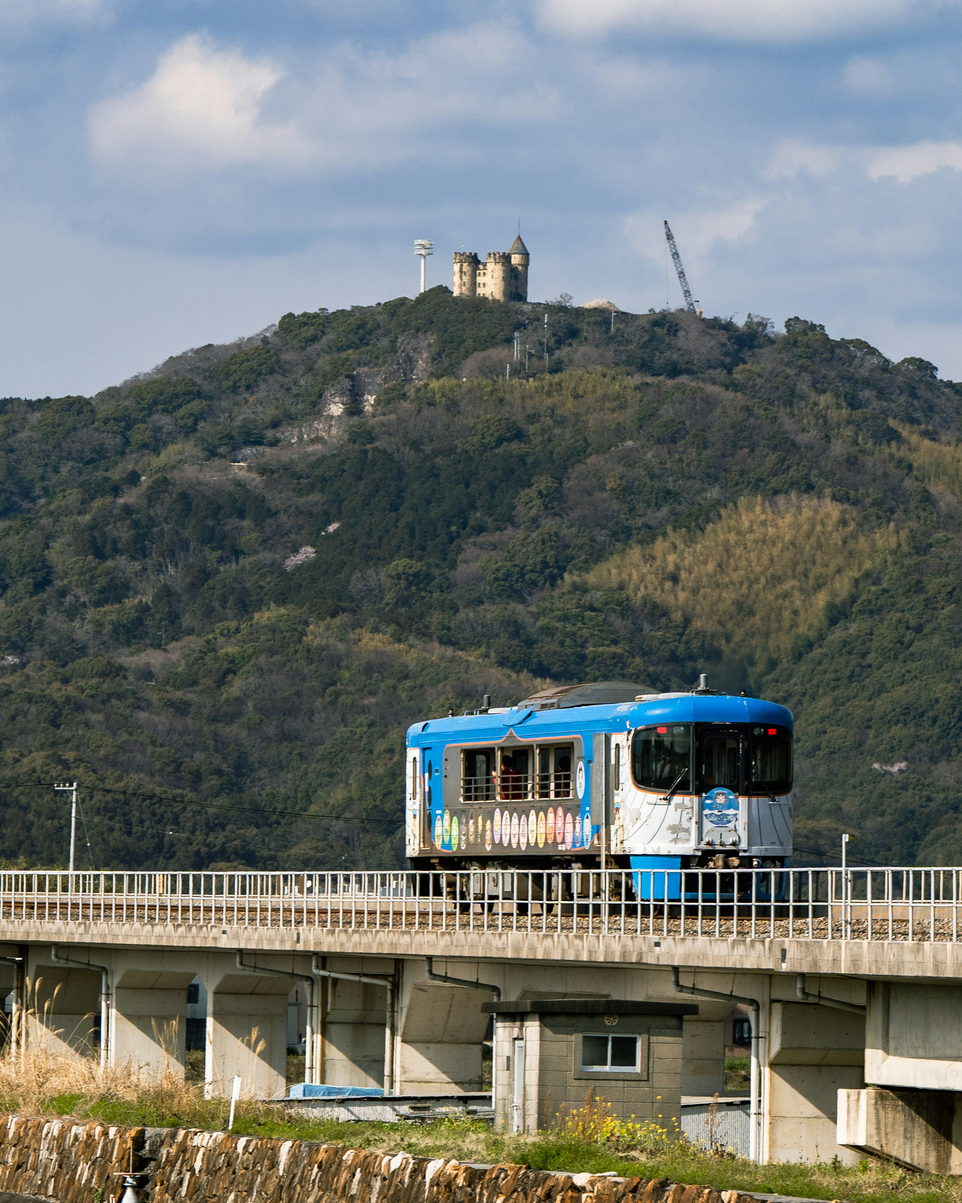 一辆蓝色电车穿过桥，背景是山和建筑物