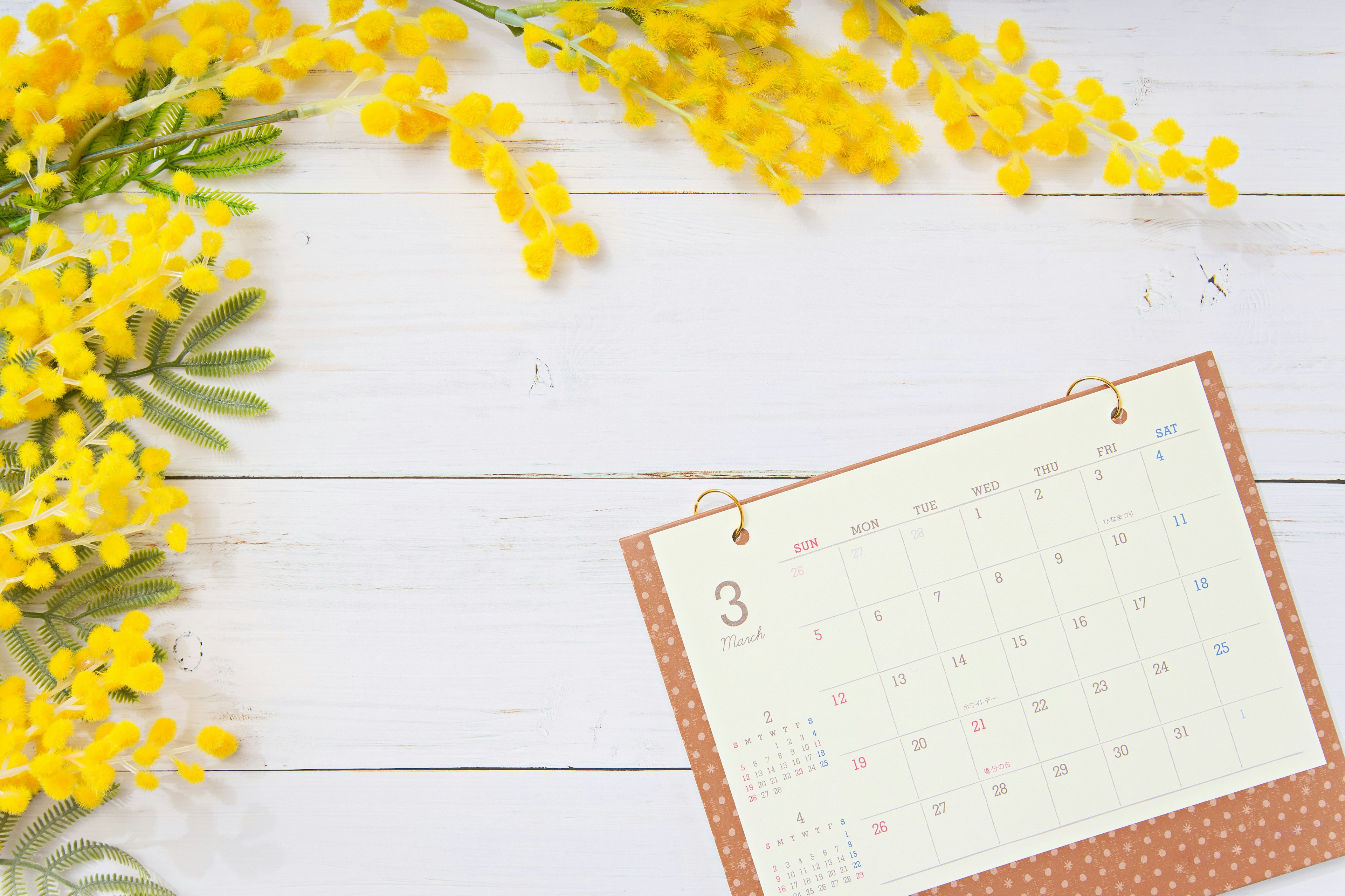 Fiori gialli e un calendario su un tavolo di legno