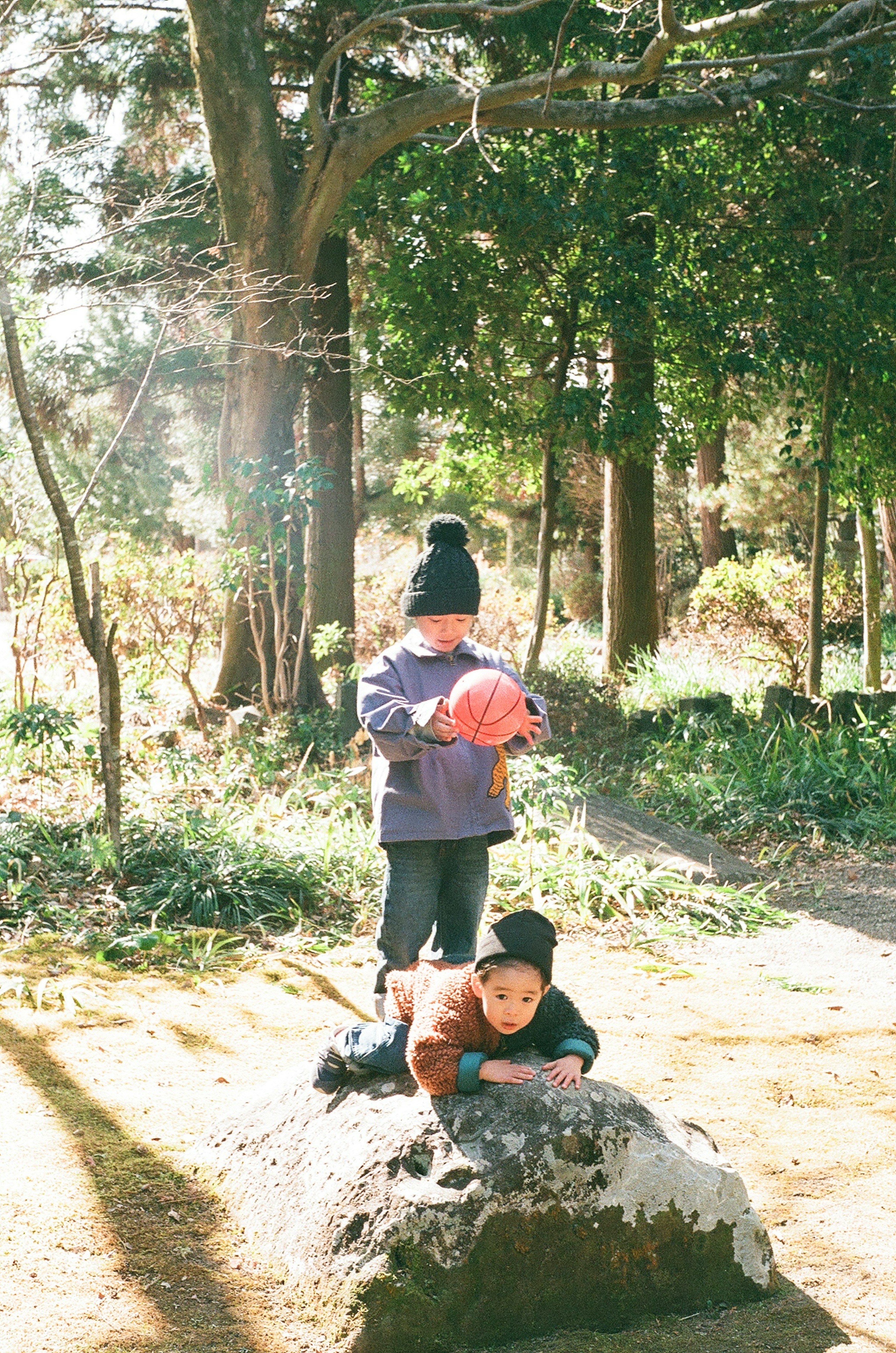 兩個孩子在公園玩 一個躺在石頭上 另一個在澆水