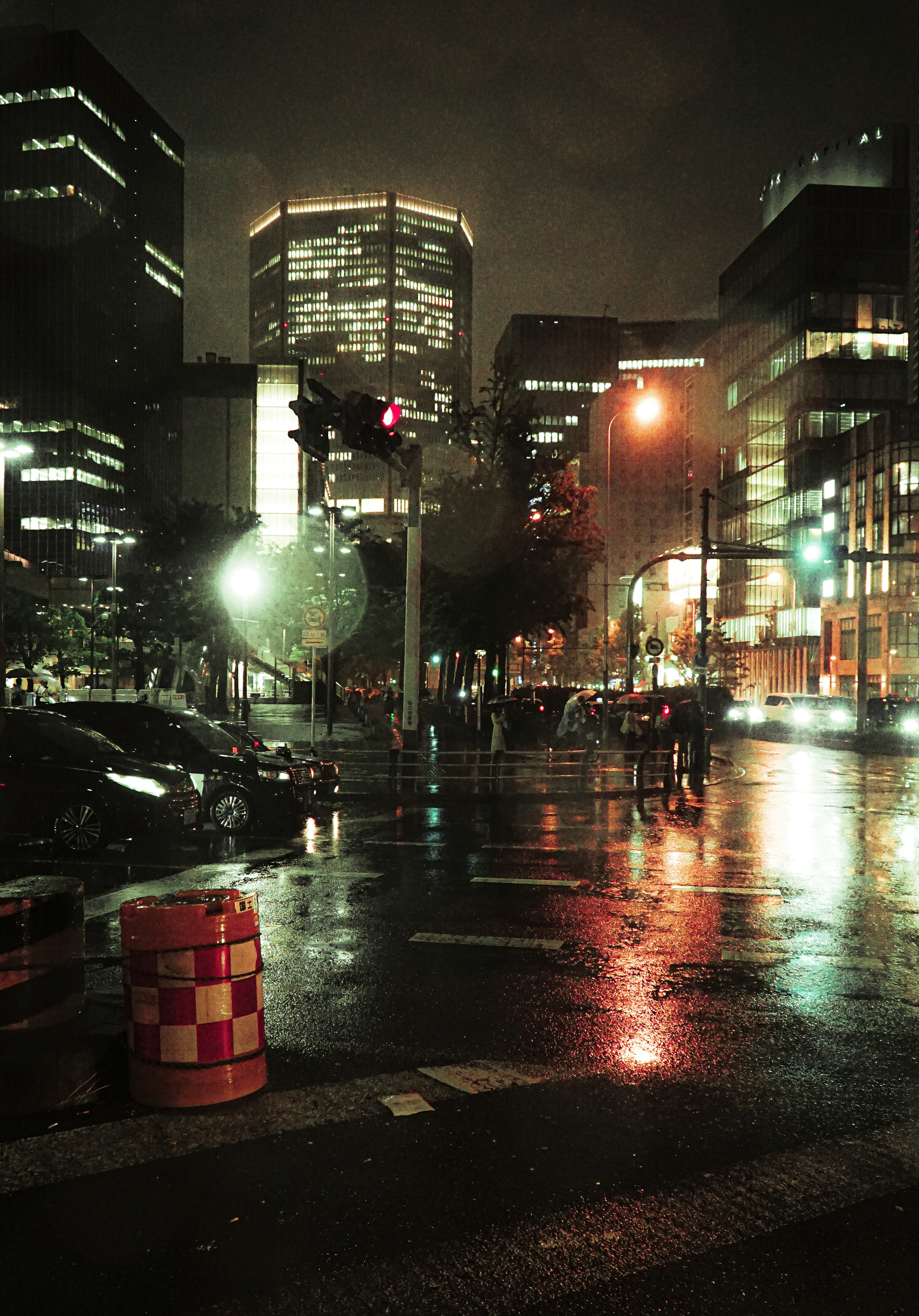 Paysage urbain nocturne avec des bâtiments illuminés et des rues mouillées reflétant la lumière