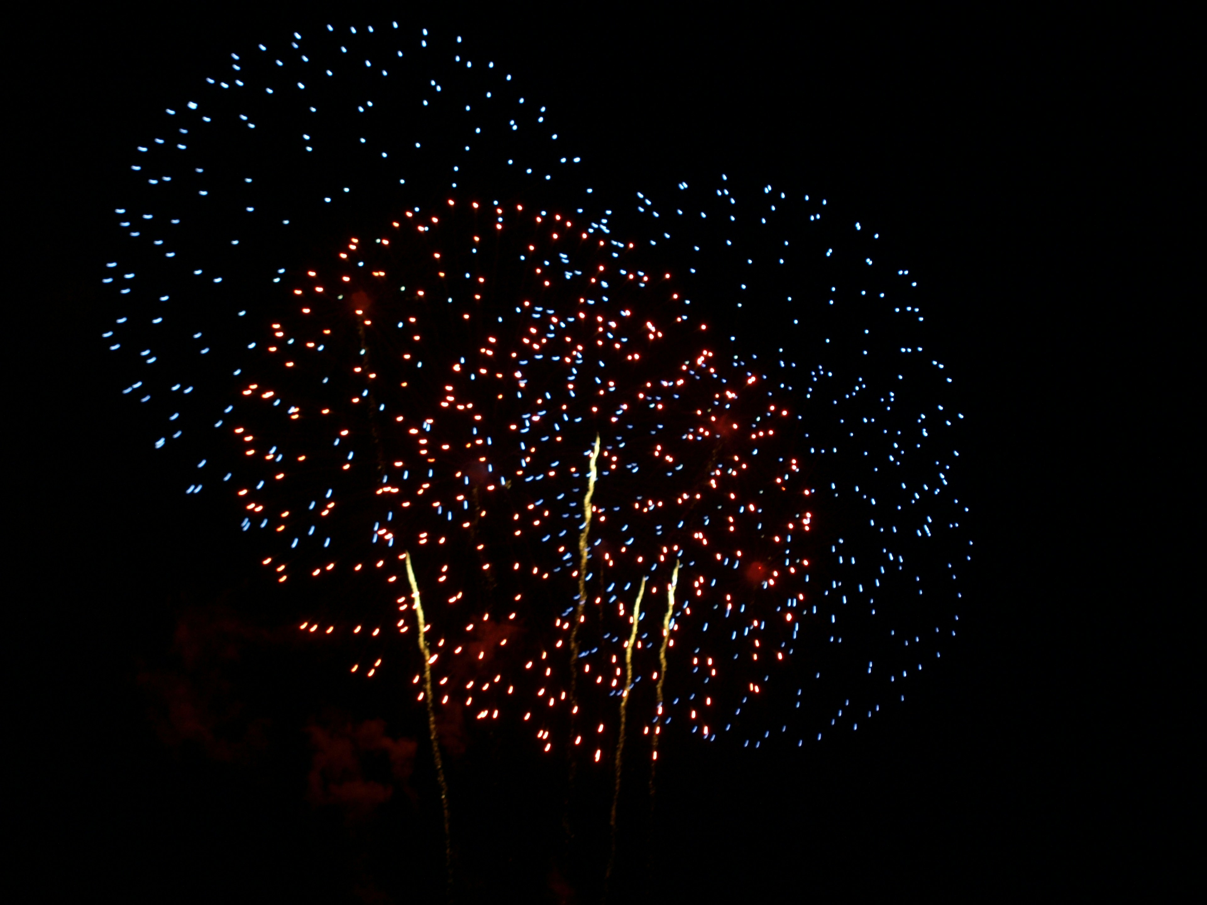 Farbige Feuerwerkshow im Nachthimmel mit roten und blauen Funken